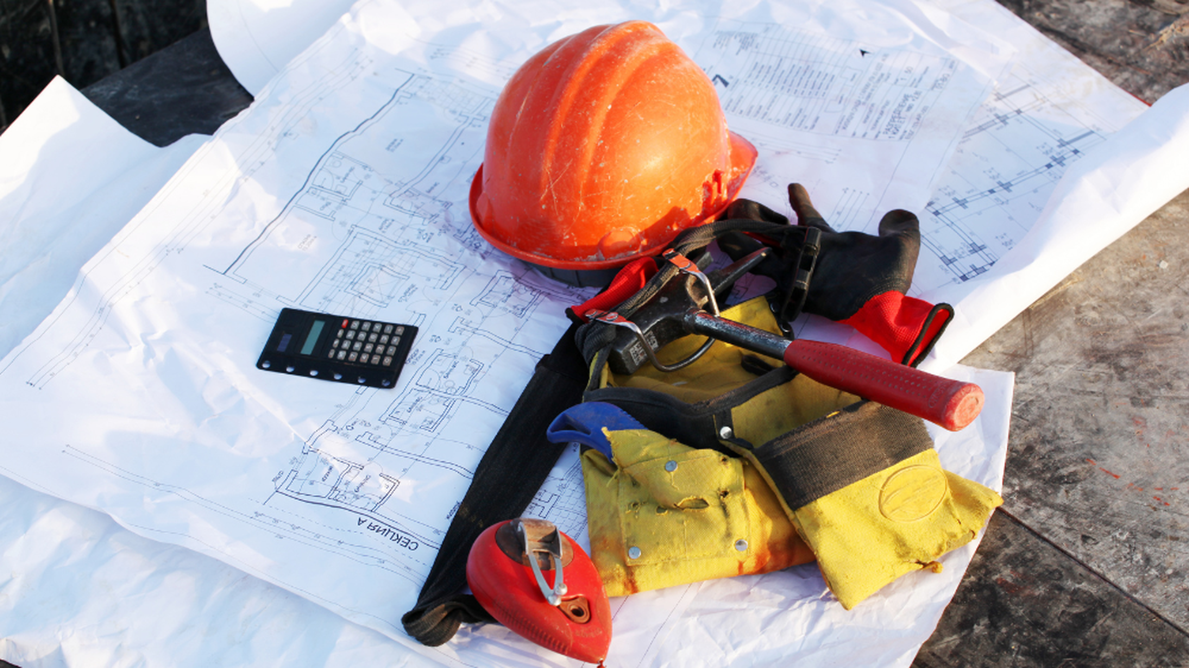 Casque de chantier, outils et plans techniques disposés au sol, illustrant l’organisation et la préparation nécessaires au suivi bennes chantier.