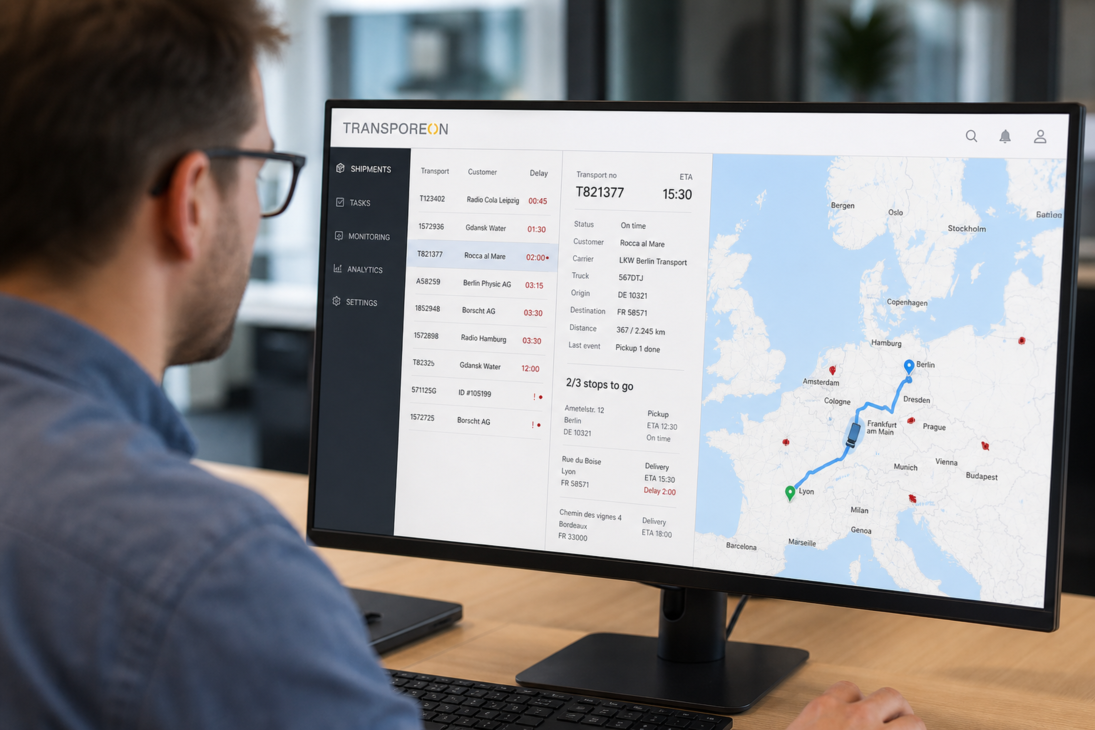 Hombre en su escritorio consultando una alternativa a Transporeon: un TMS con mapa y seguimiento de envíos por toda Europa.
