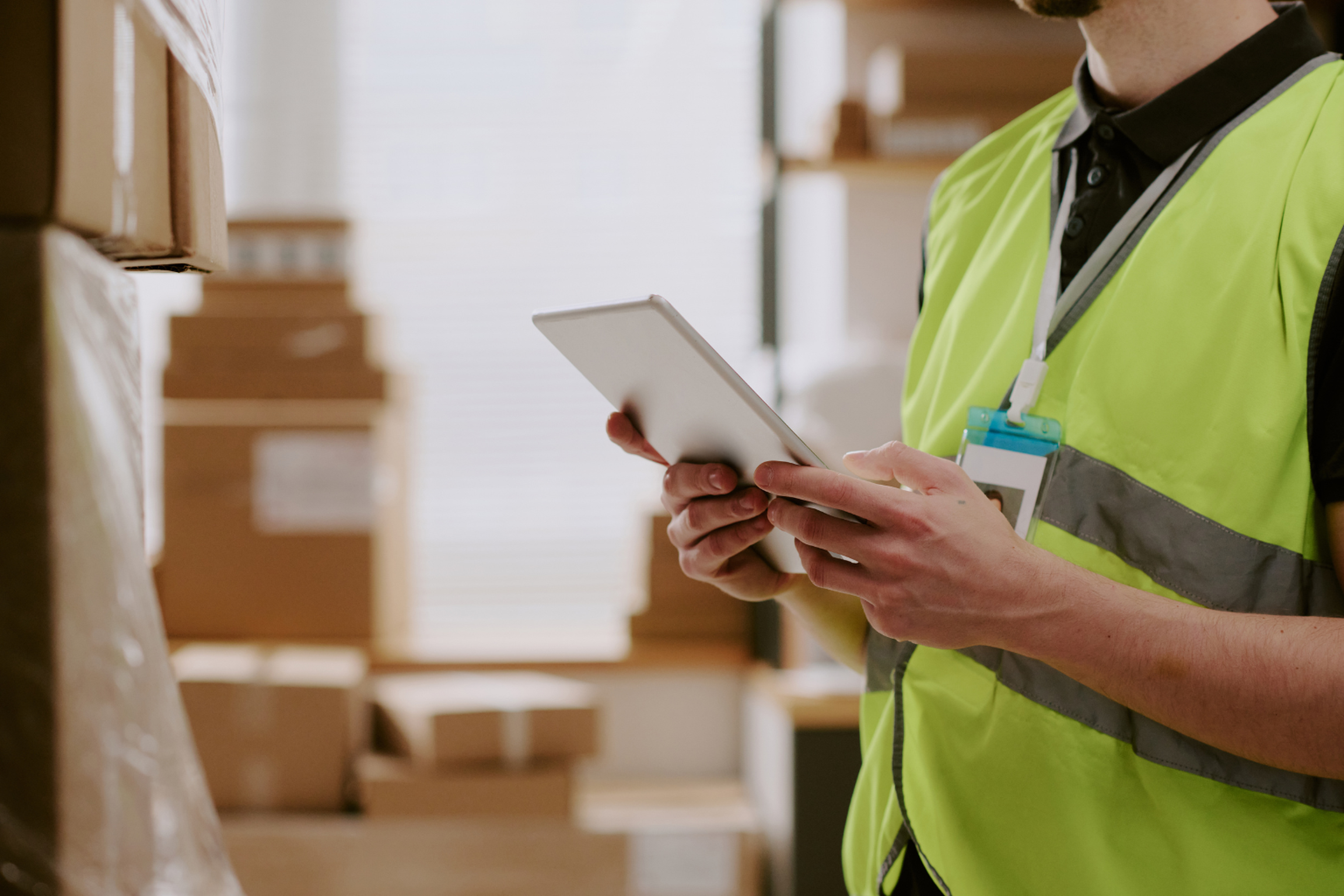 Employé en gilet haute visibilité utilisant une tablette dans un entrepôt avec TMS chargeur.