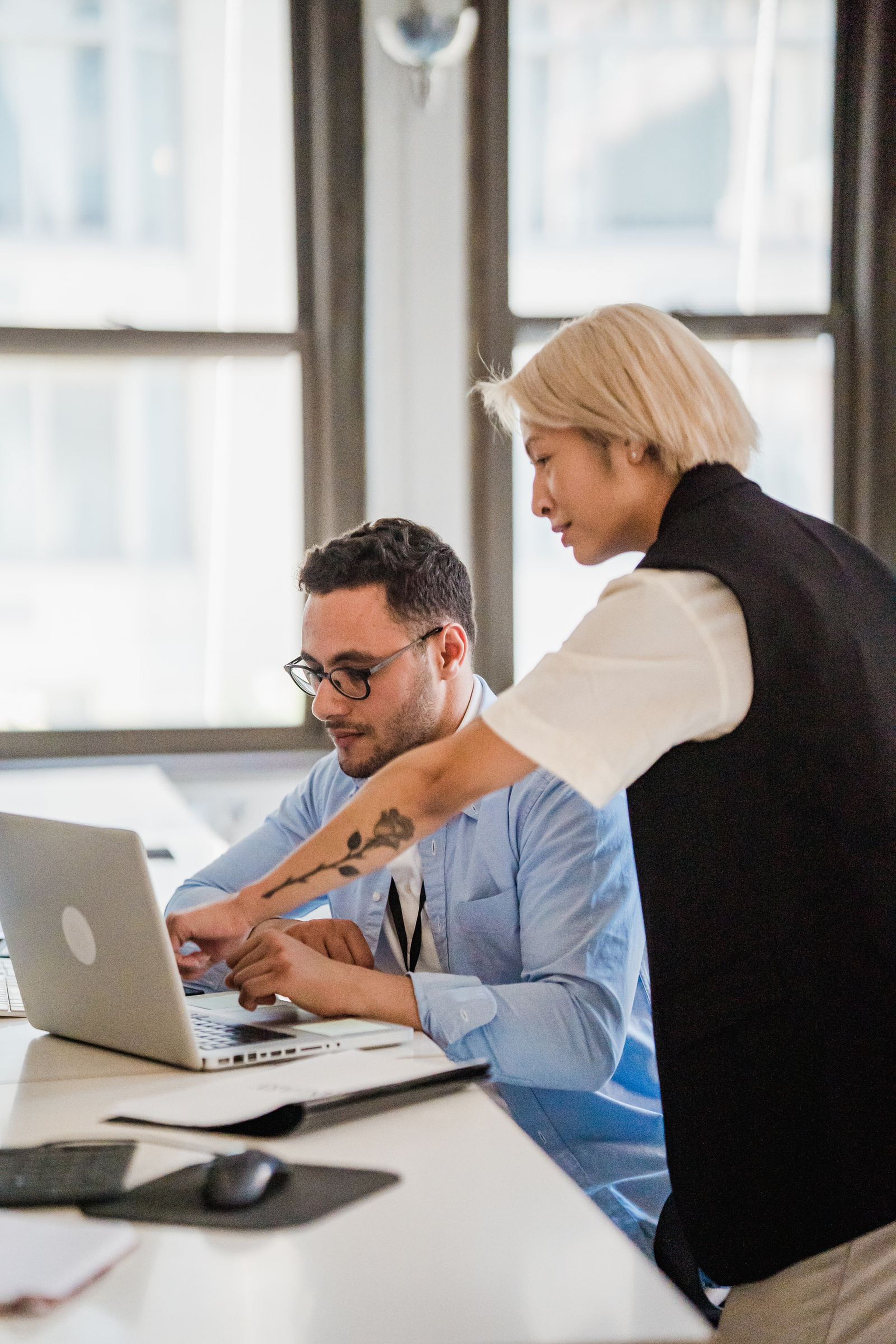 Two operations colleagues reviewing a shipper's shipment status on a laptop at an office desk