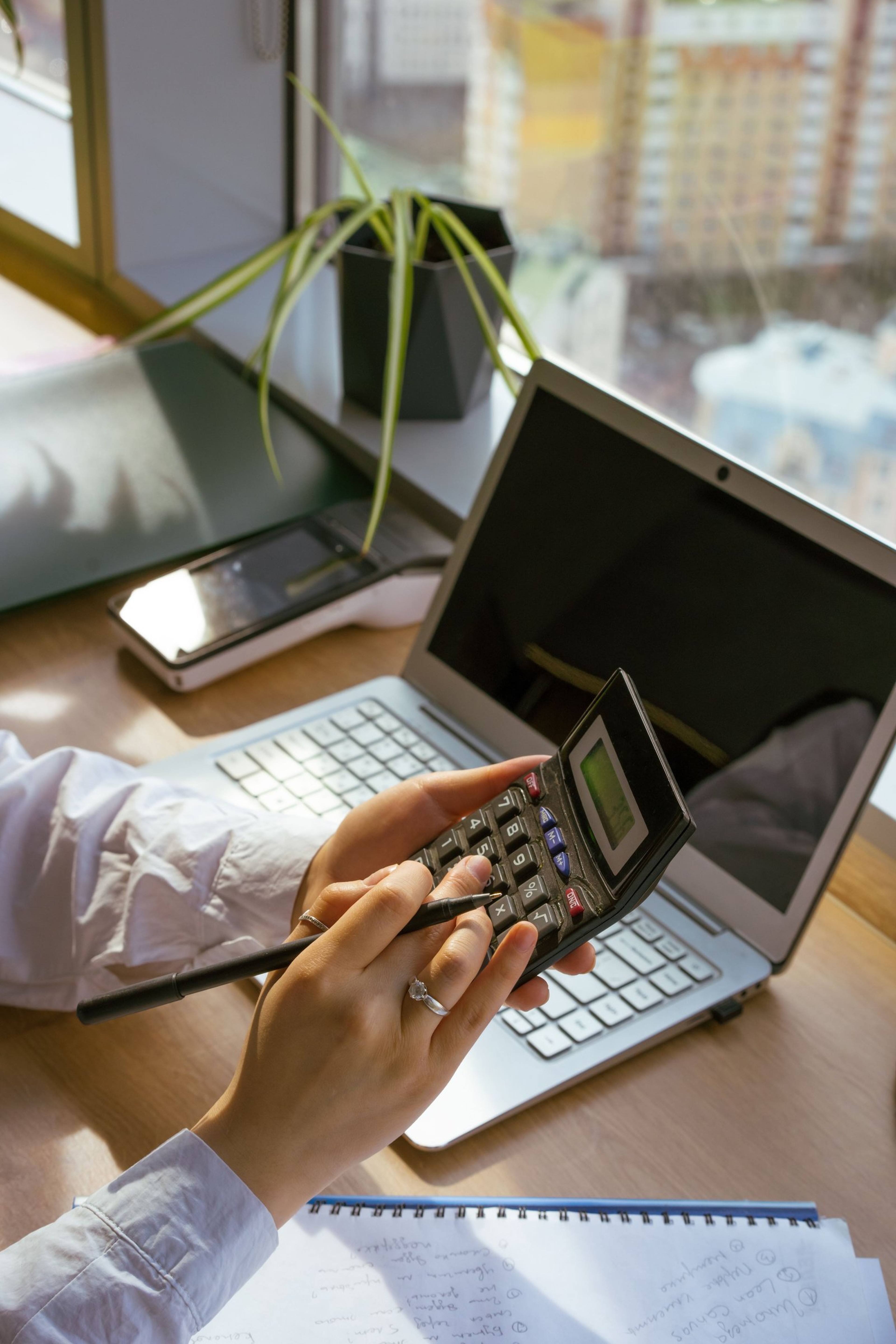 Fleet finance manager reconciling truck mileage and invoice data on a laptop and calculator