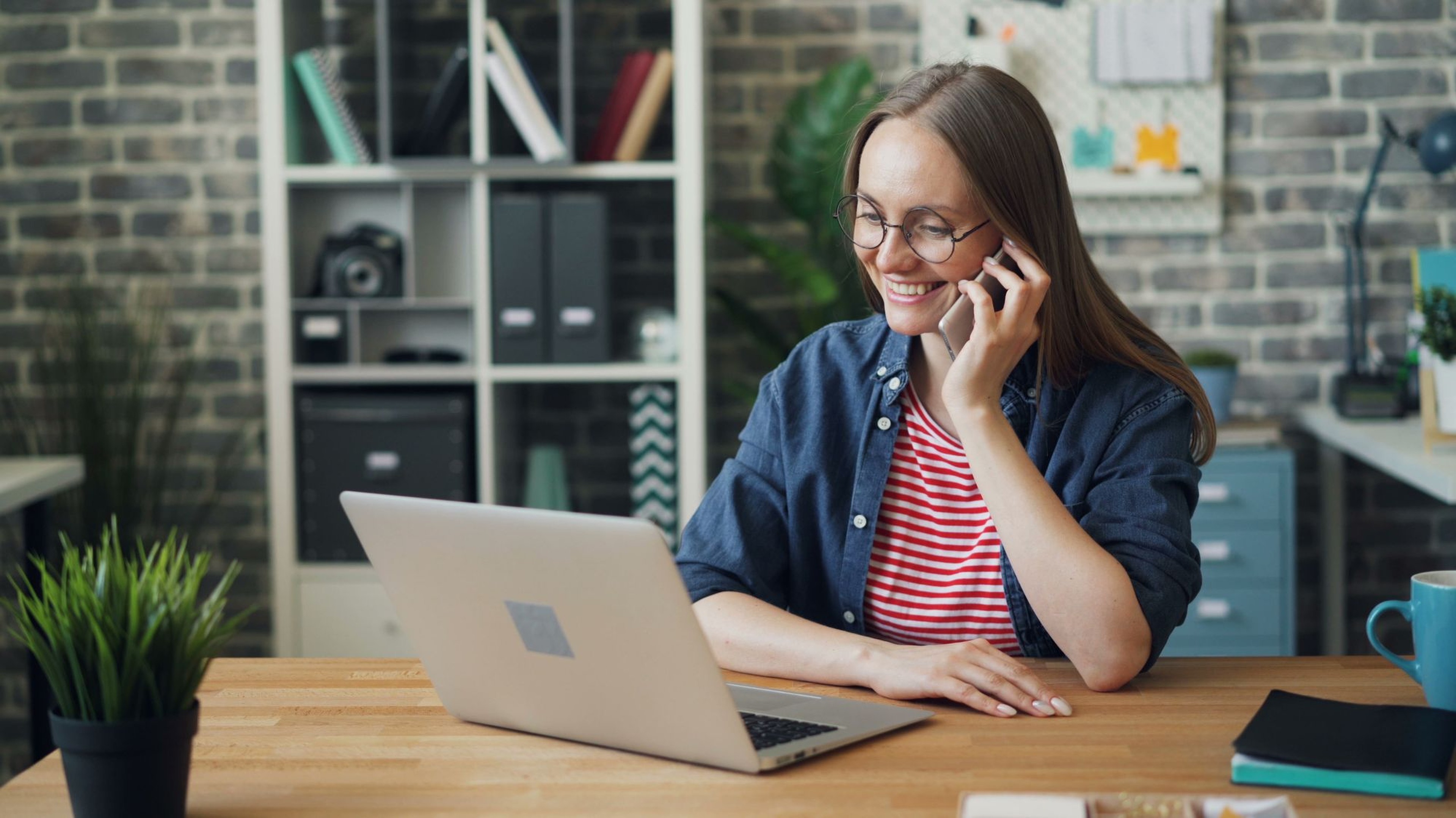 Operations manager on the phone at her desk in a modern office, fielding a shipment status update call