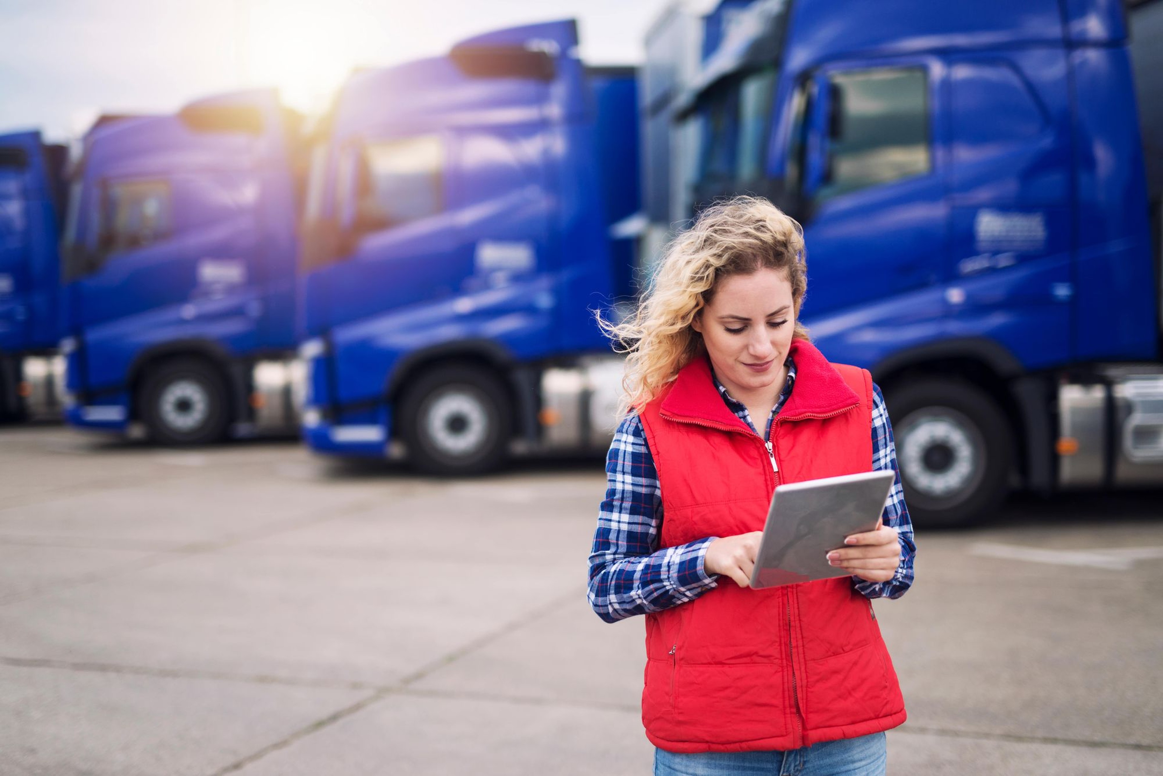 Femme devant une flotte de camion avec une tablette dans les mains