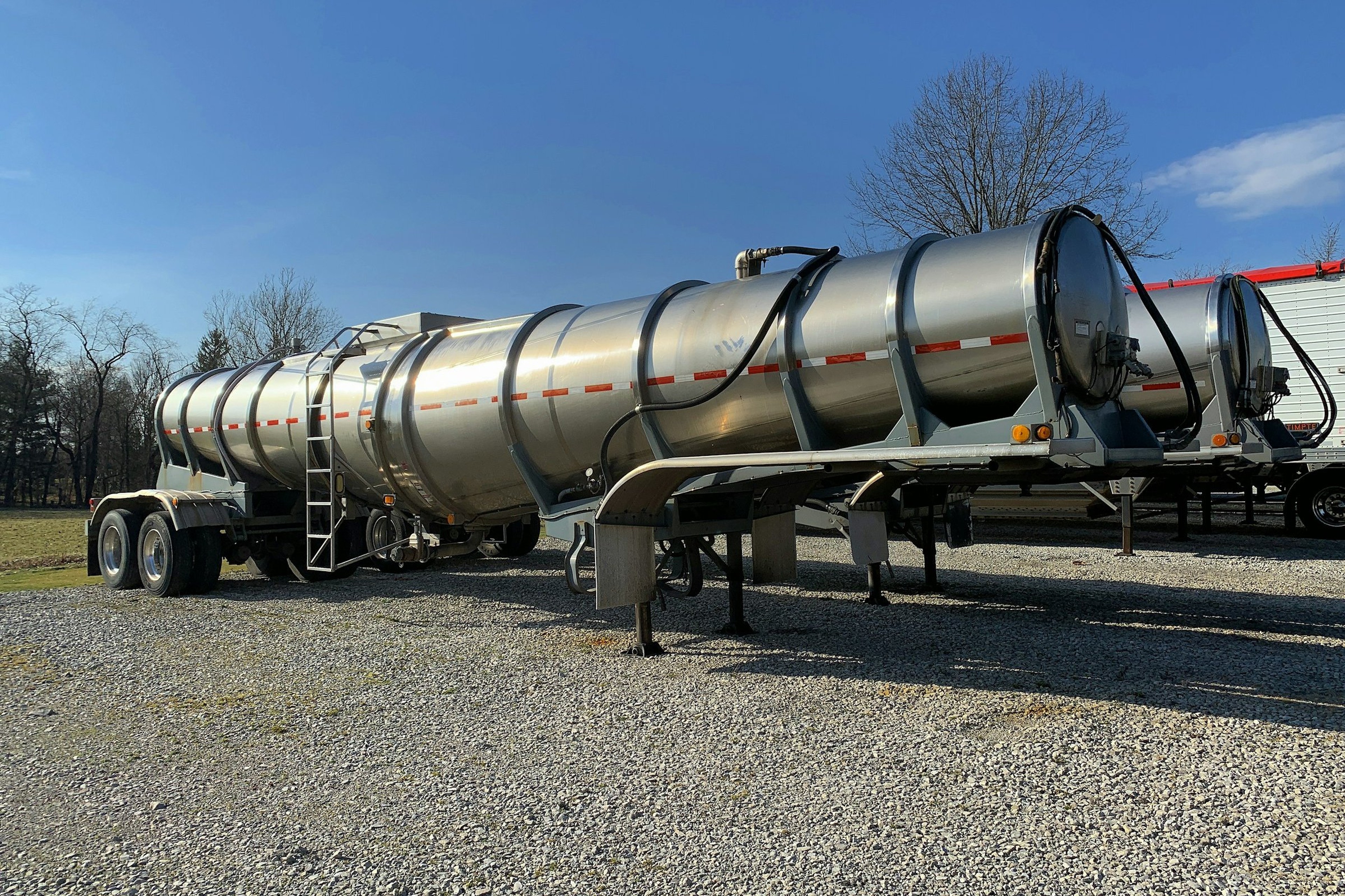 Stainless steel liquid bulk tank trailers parked in a carrier's gravel yard in Ohio