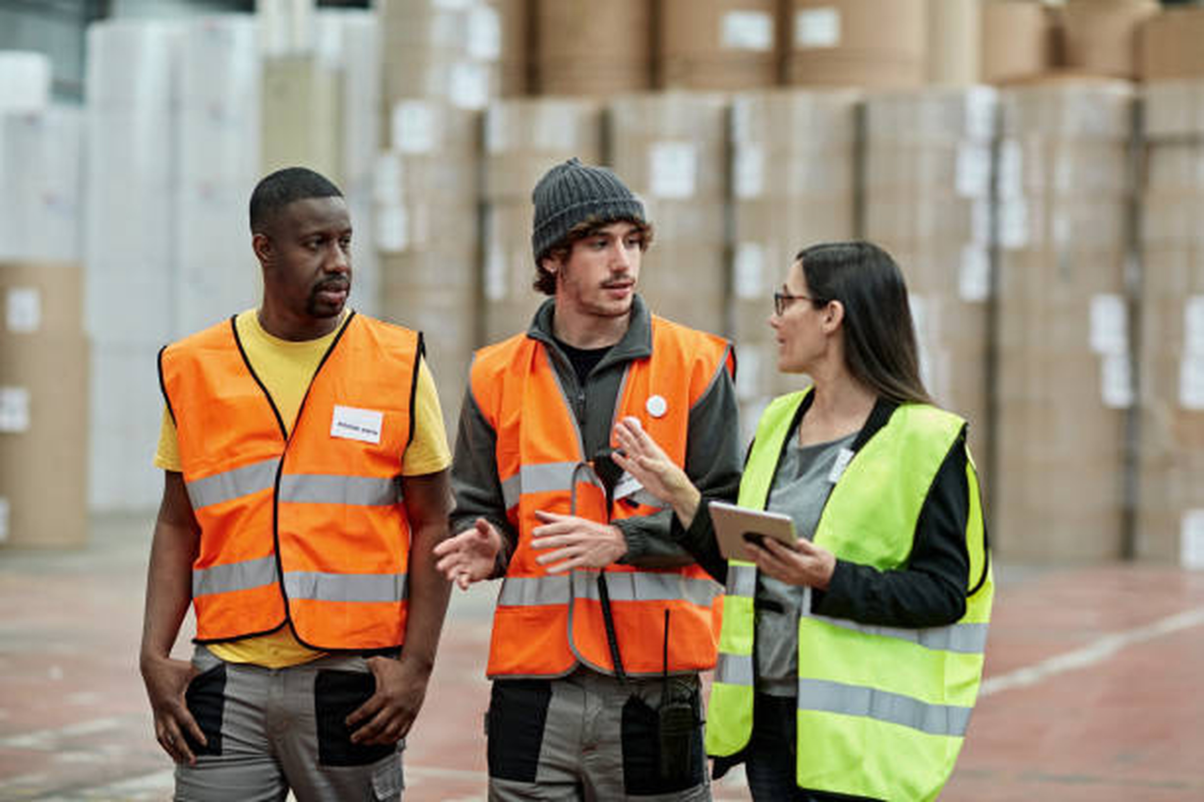 Femme manager donne instructions à deux employés logistiques