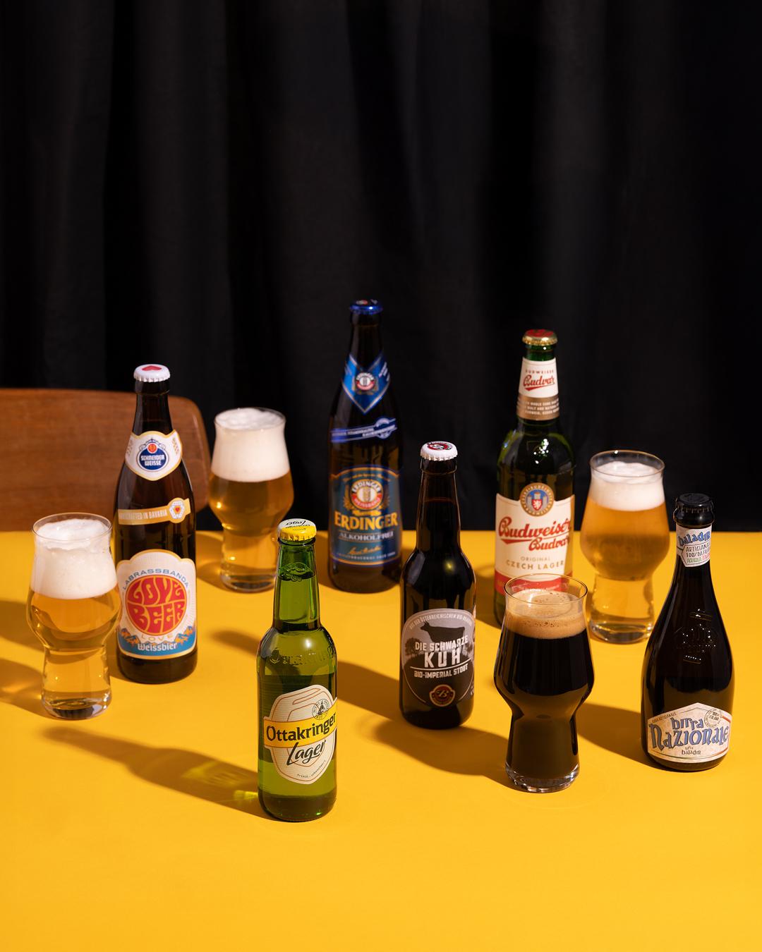 Biersorten in Flaschen und Gläsern auf gelbem Grund