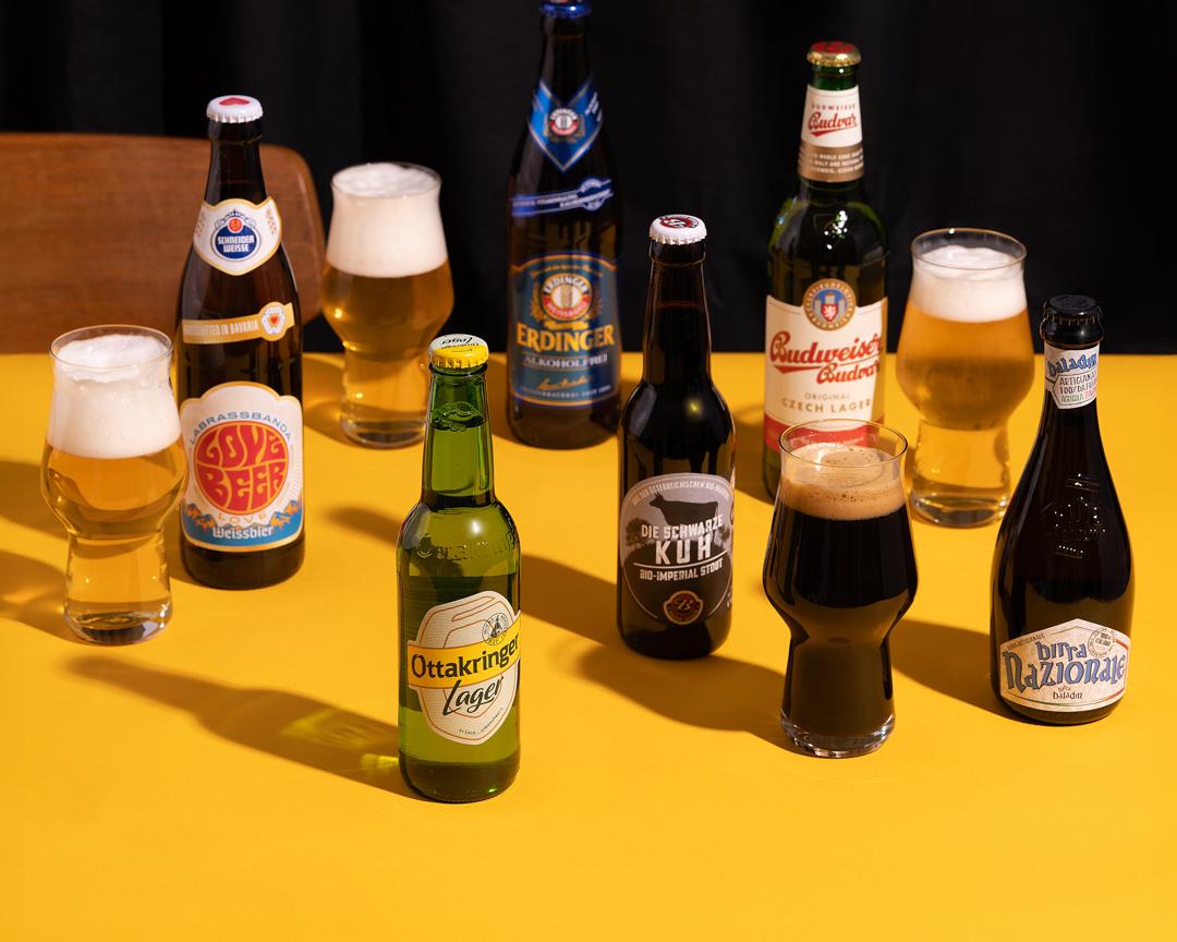 Biersorten in Flaschen und Gläsern auf gelbem Grund