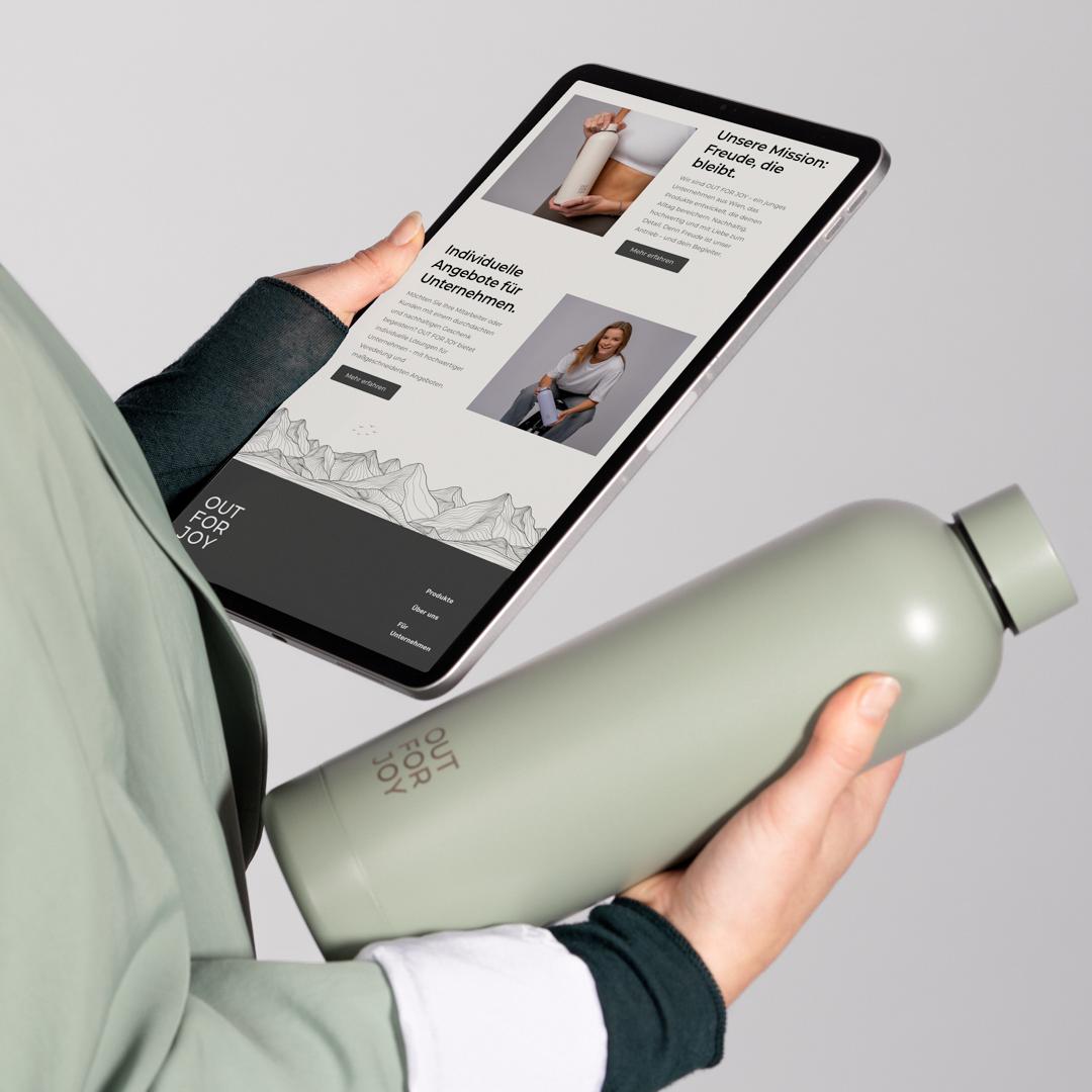 Tablet mit Website neben einer grünen Trinkflasche in der Hand