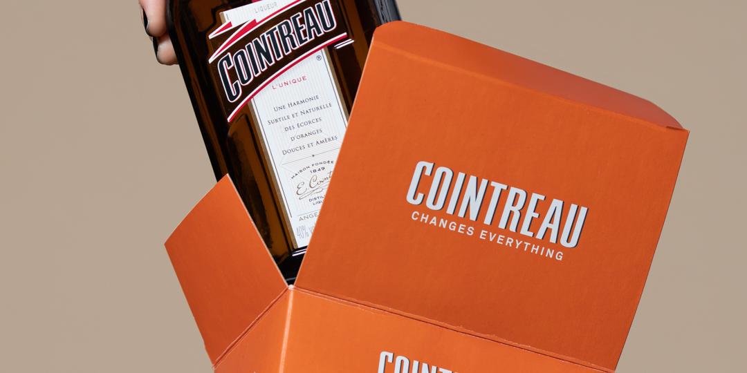 Hand zieht eine Cointreau-Flasche aus der orangen Geschenkbox