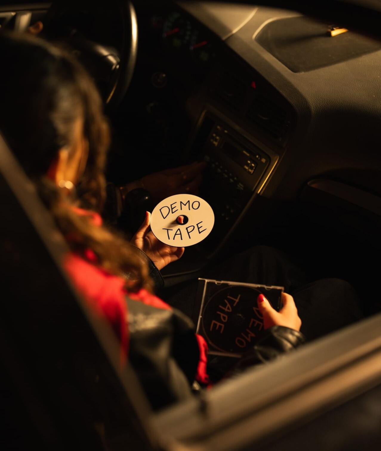 Hand hält ein Demo-Tape im dunklen Auto