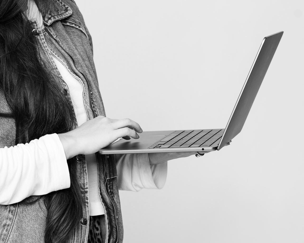 Schwarzweiß: Person tippt im Stehen auf einem Laptop