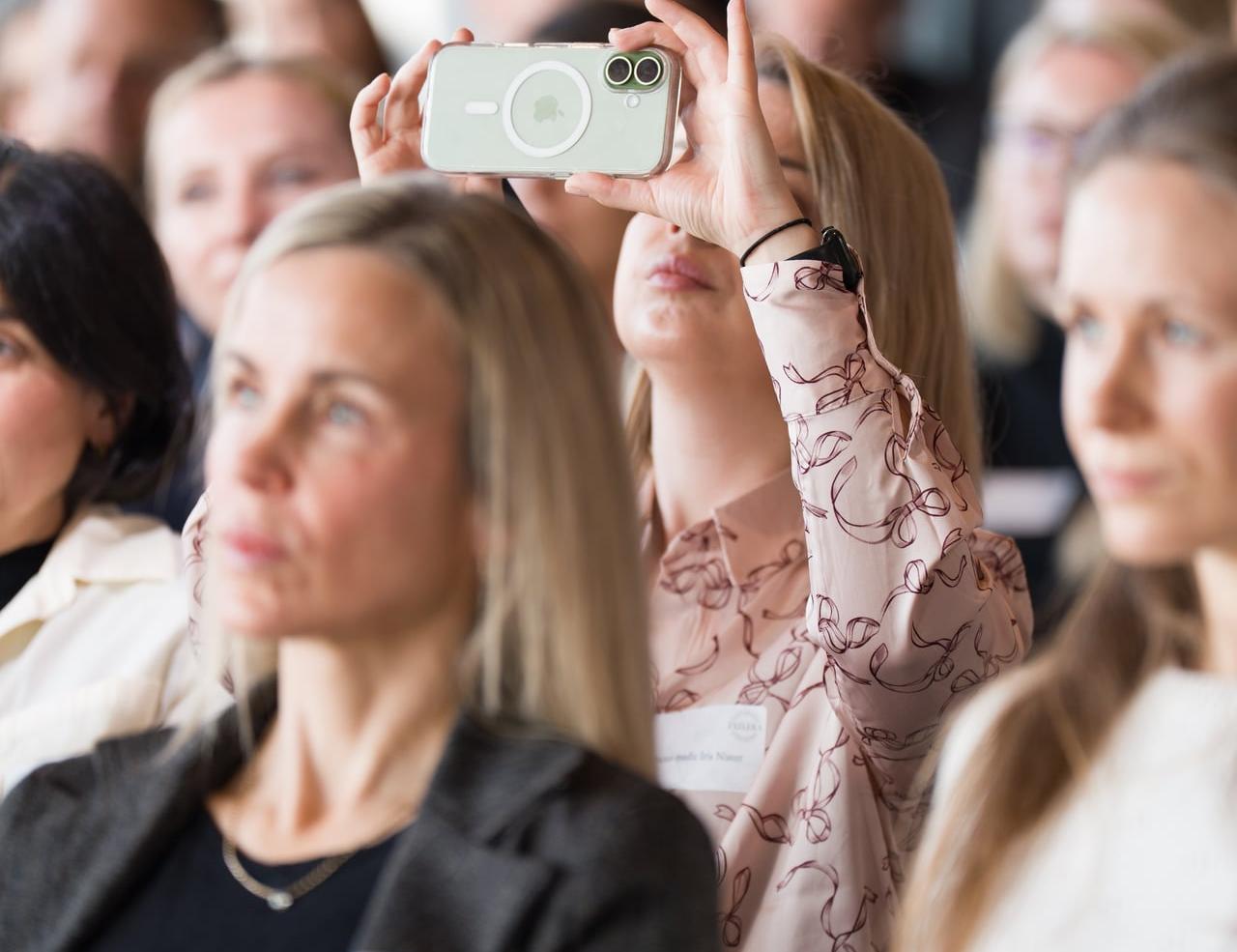 Teilnehmerin filmt eine Präsentation mit dem Smartphone