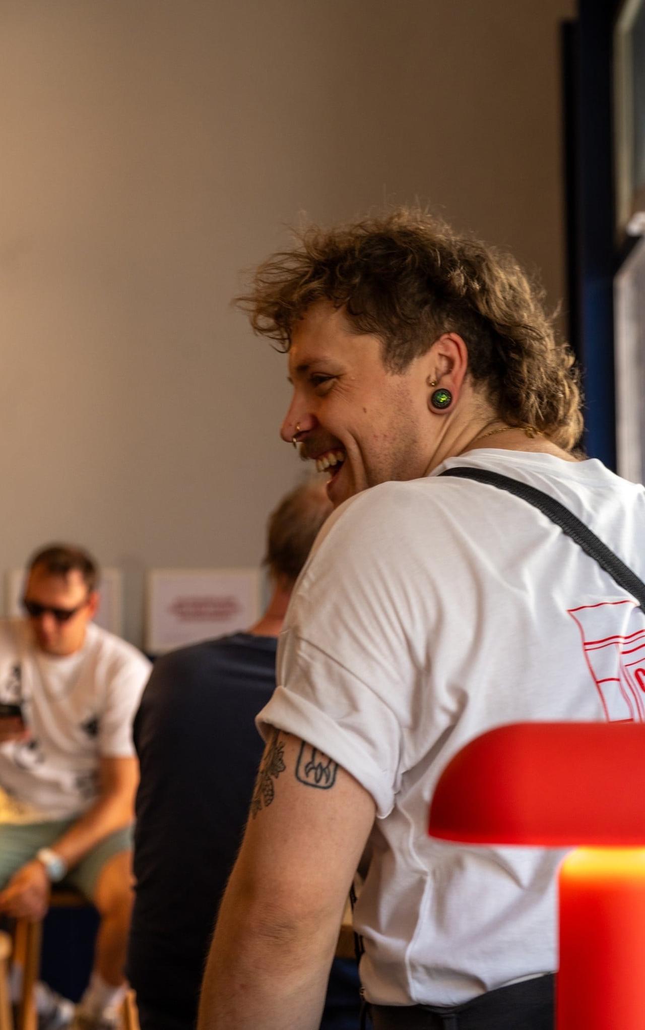 Gast im weißen T-Shirt lacht in der Bar