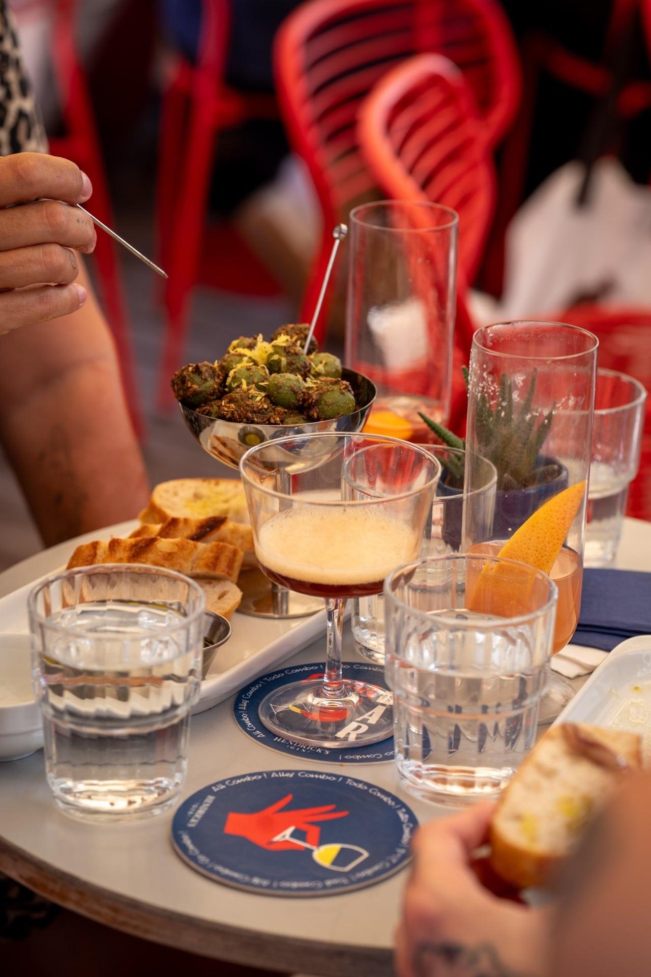 Tisch mit Espresso Martini, Oliven, Brot und Combo-Bar-Untersetzern