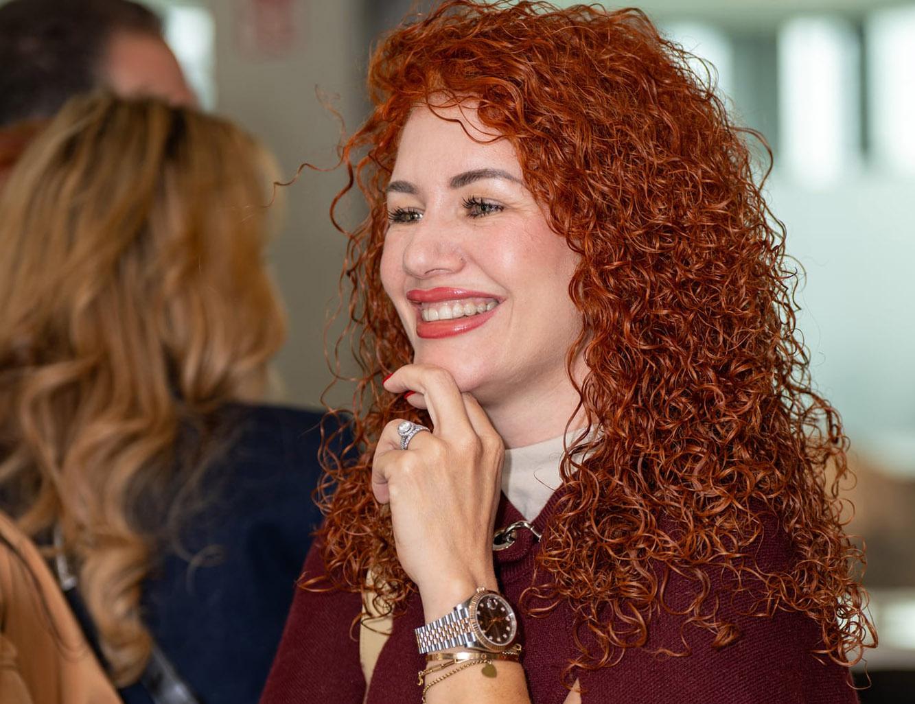 Frau mit roten Locken lacht bei einer Abendveranstaltung
