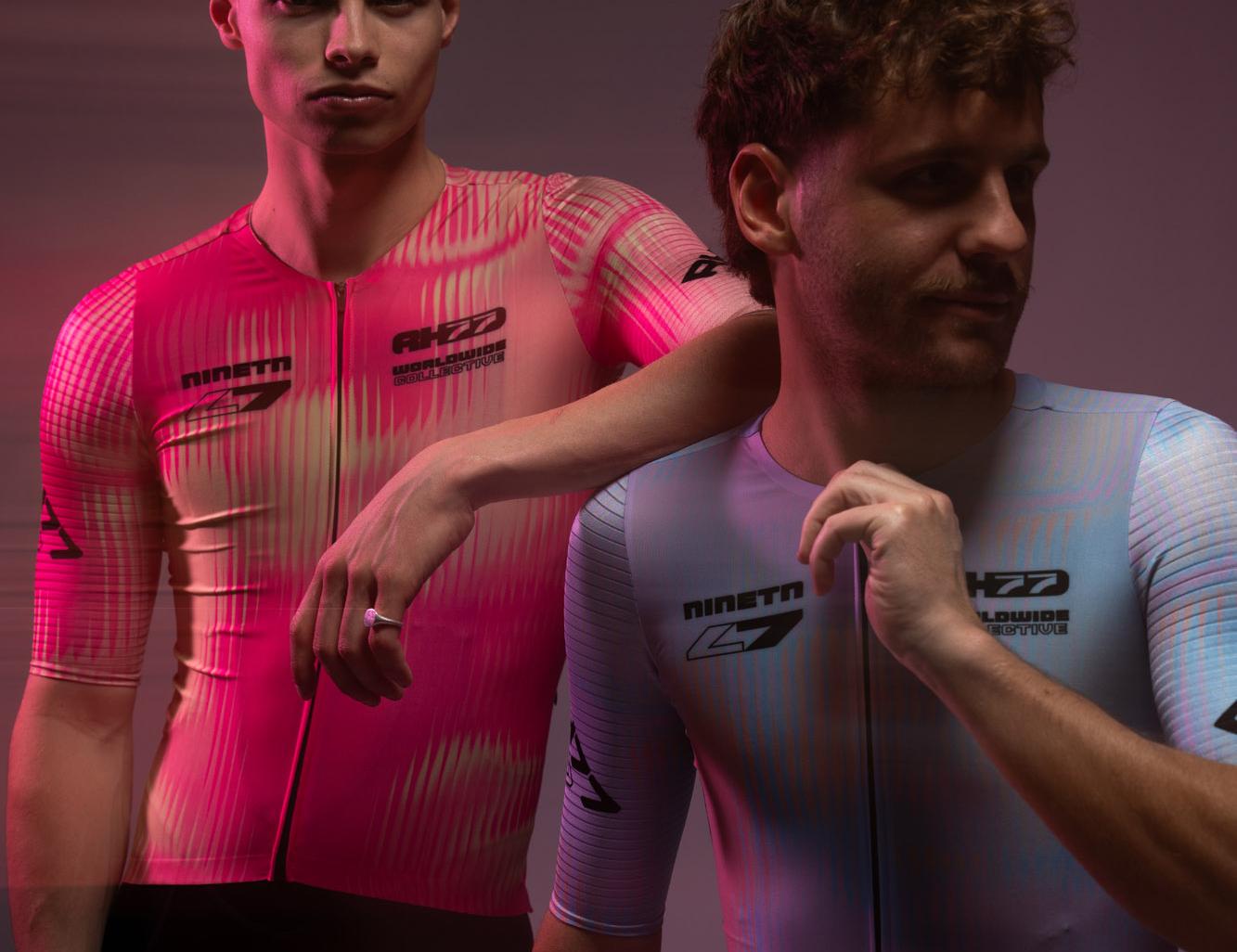 Zwei Radsportler in pinken und hellen Rennanzügen im Studiolicht