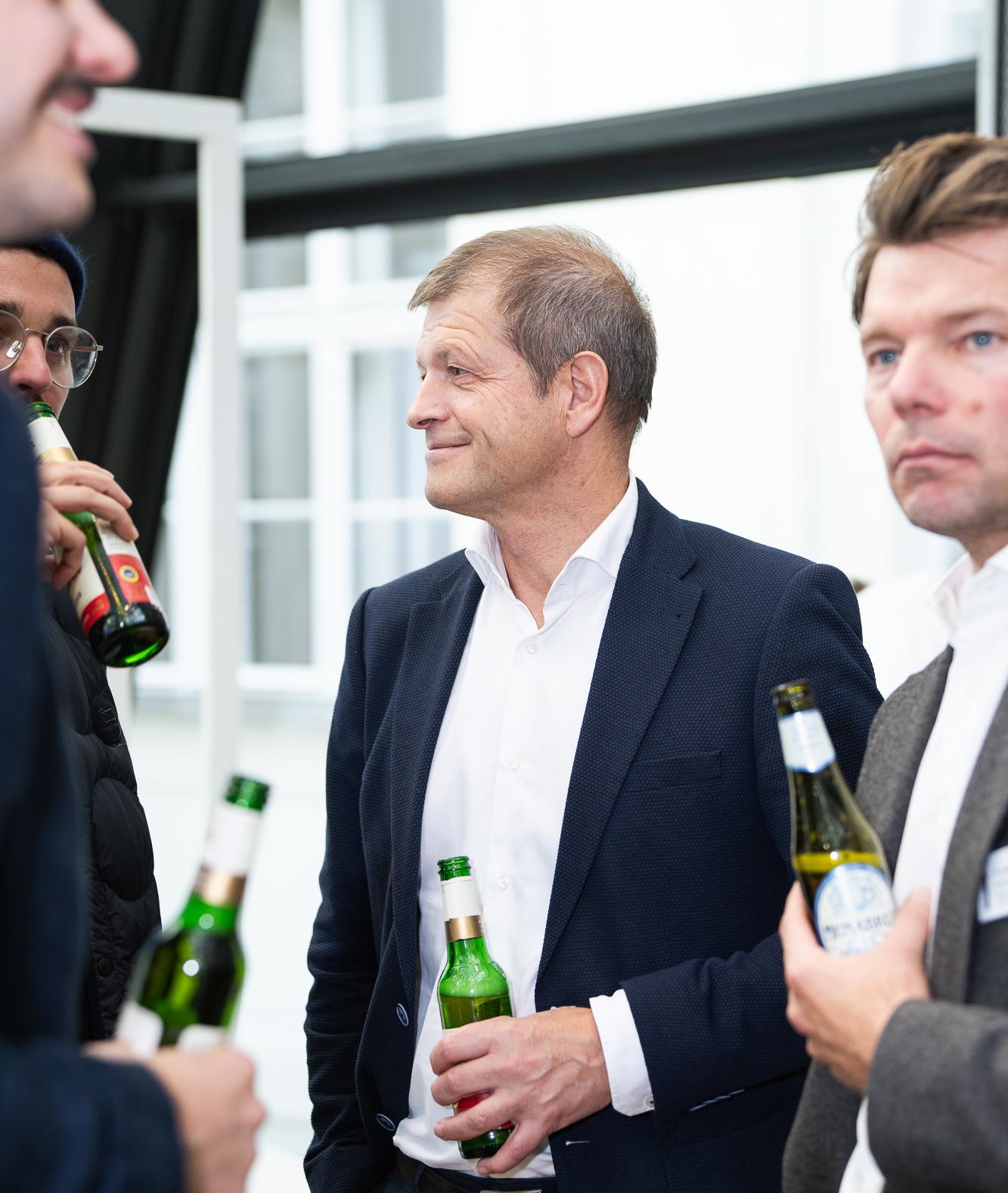 Zwei Männer im Gespräch mit Weinflaschen in der Hand