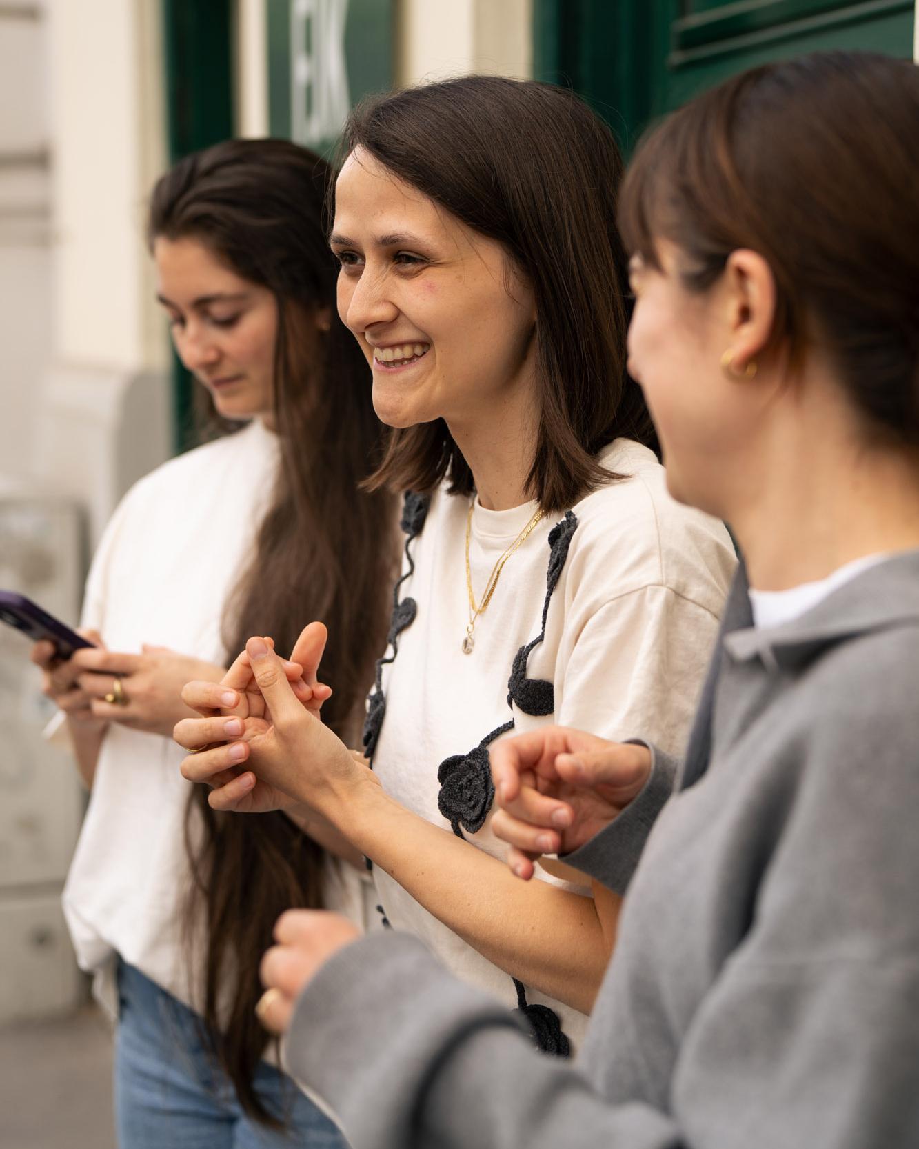 Drei Kolleginnen im Gespräch, eine hält ein Smartphone