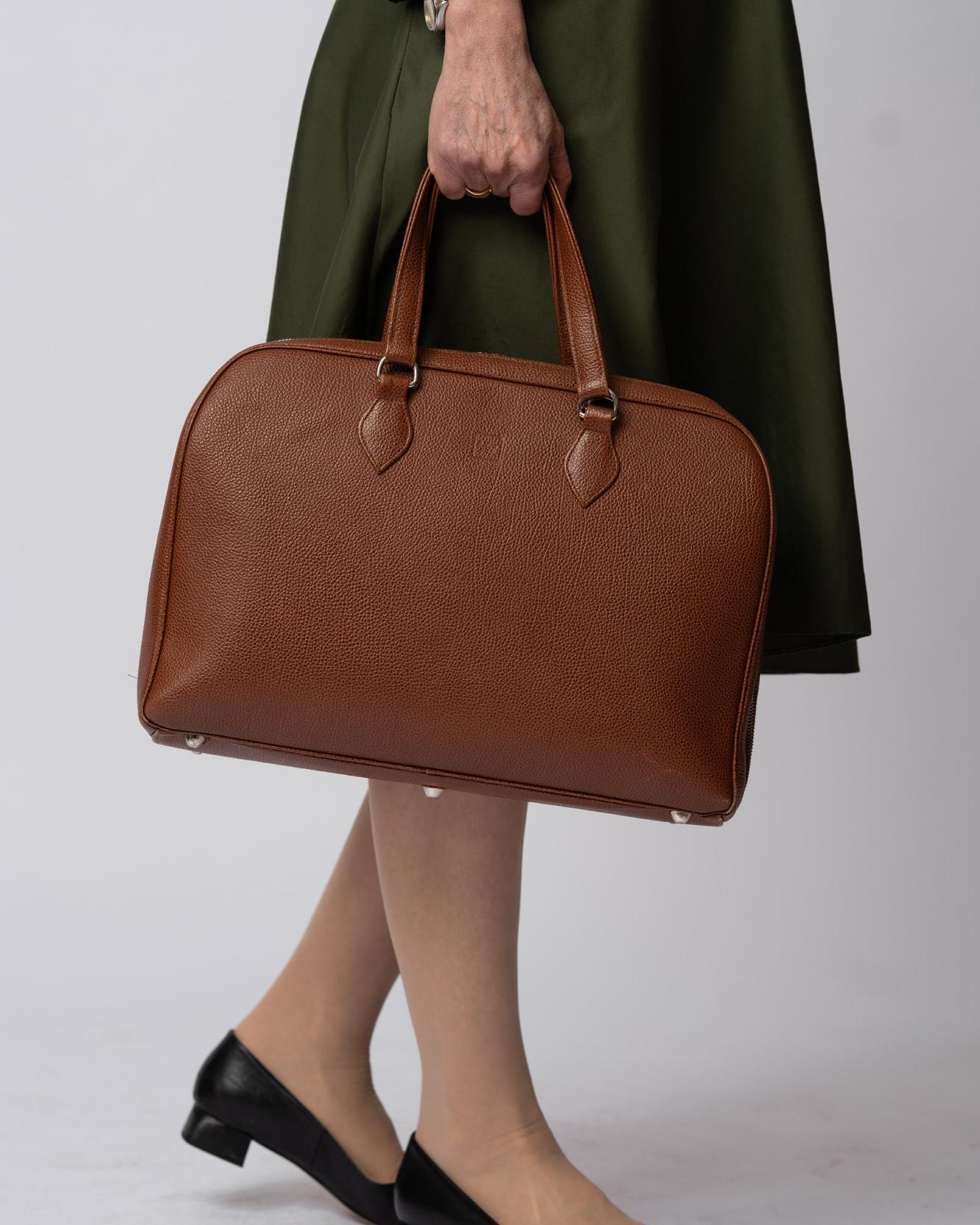Braune Ledertasche mit Griffen vor dunklem Hintergrund