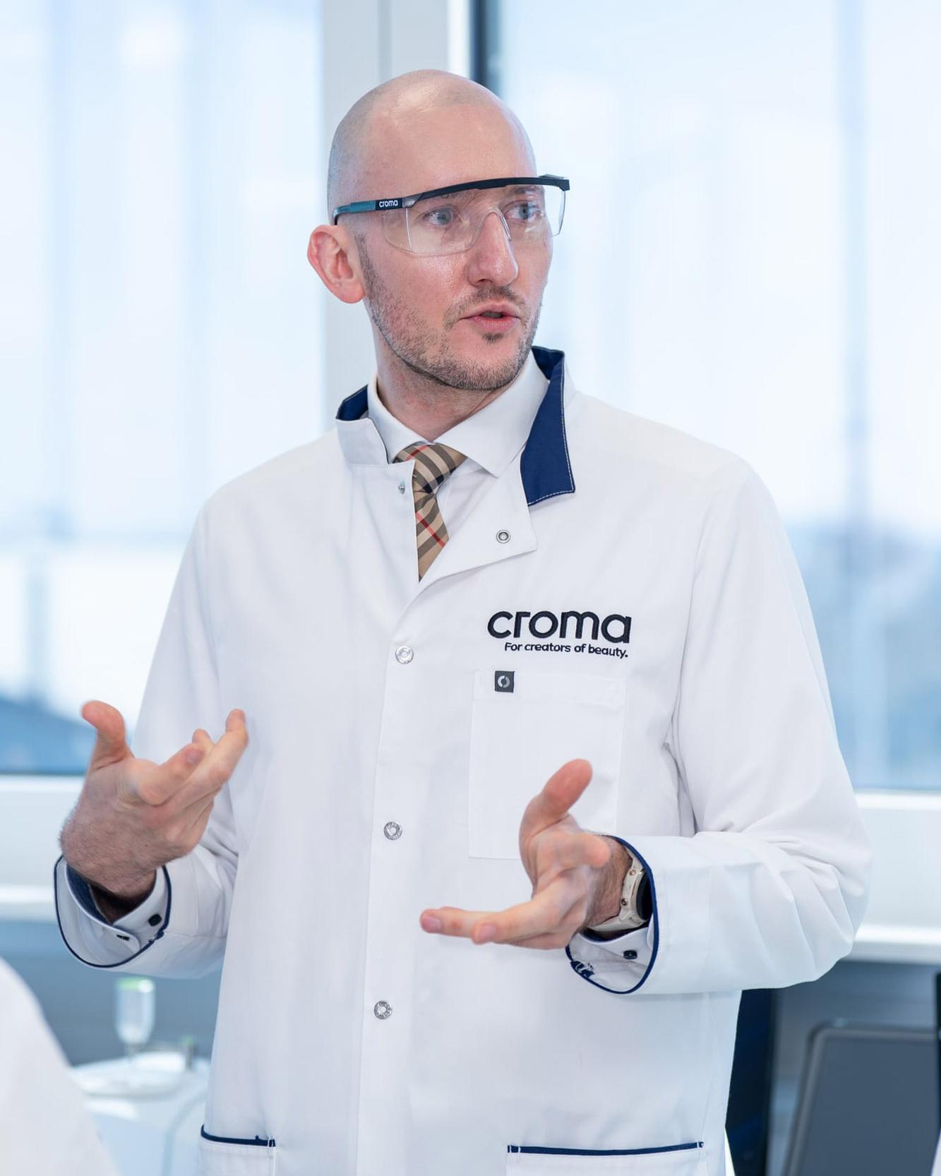 Mann im Croma-Laborkittel gestikuliert während eines Vortrags
