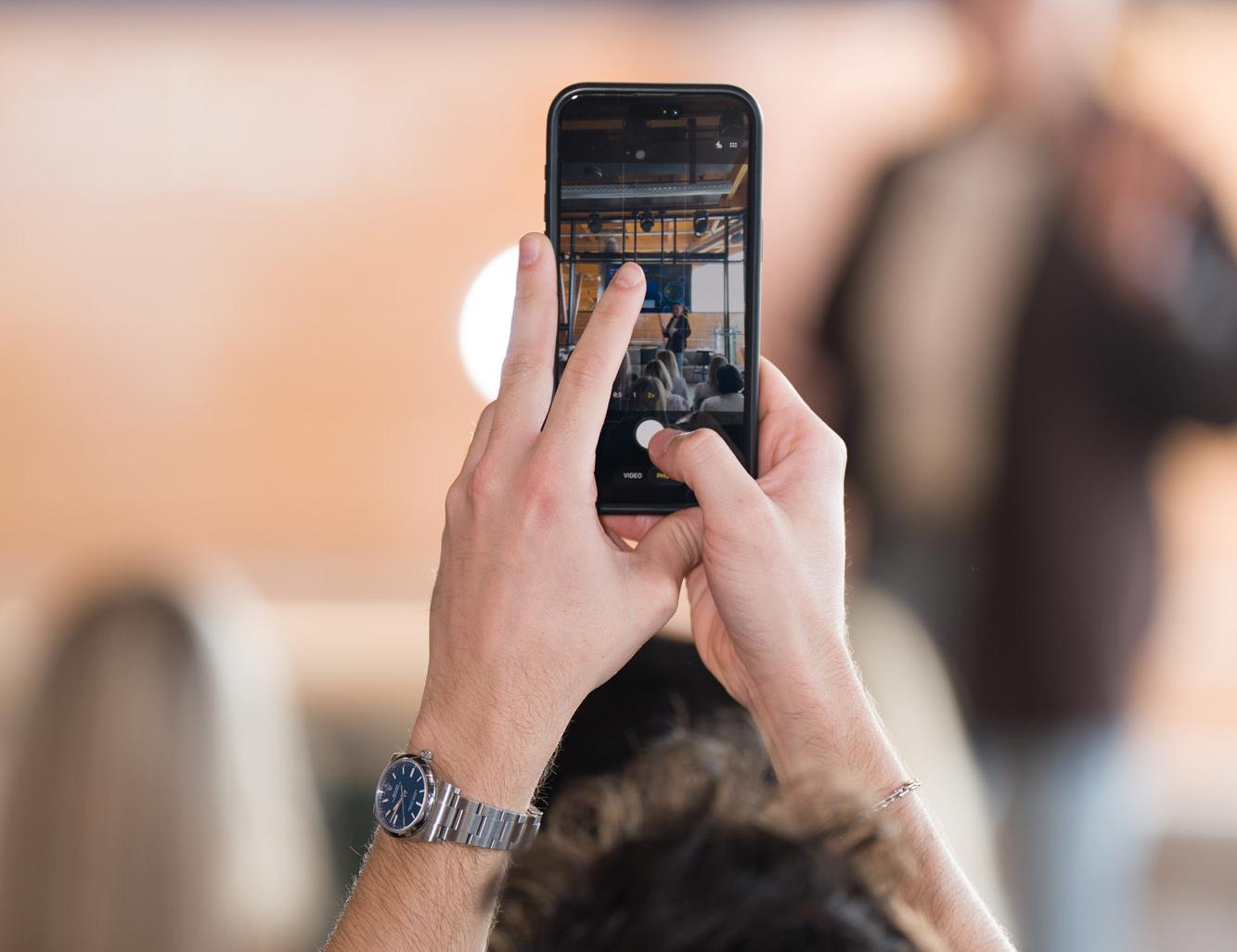Hände filmen eine Bühne mit dem Smartphone