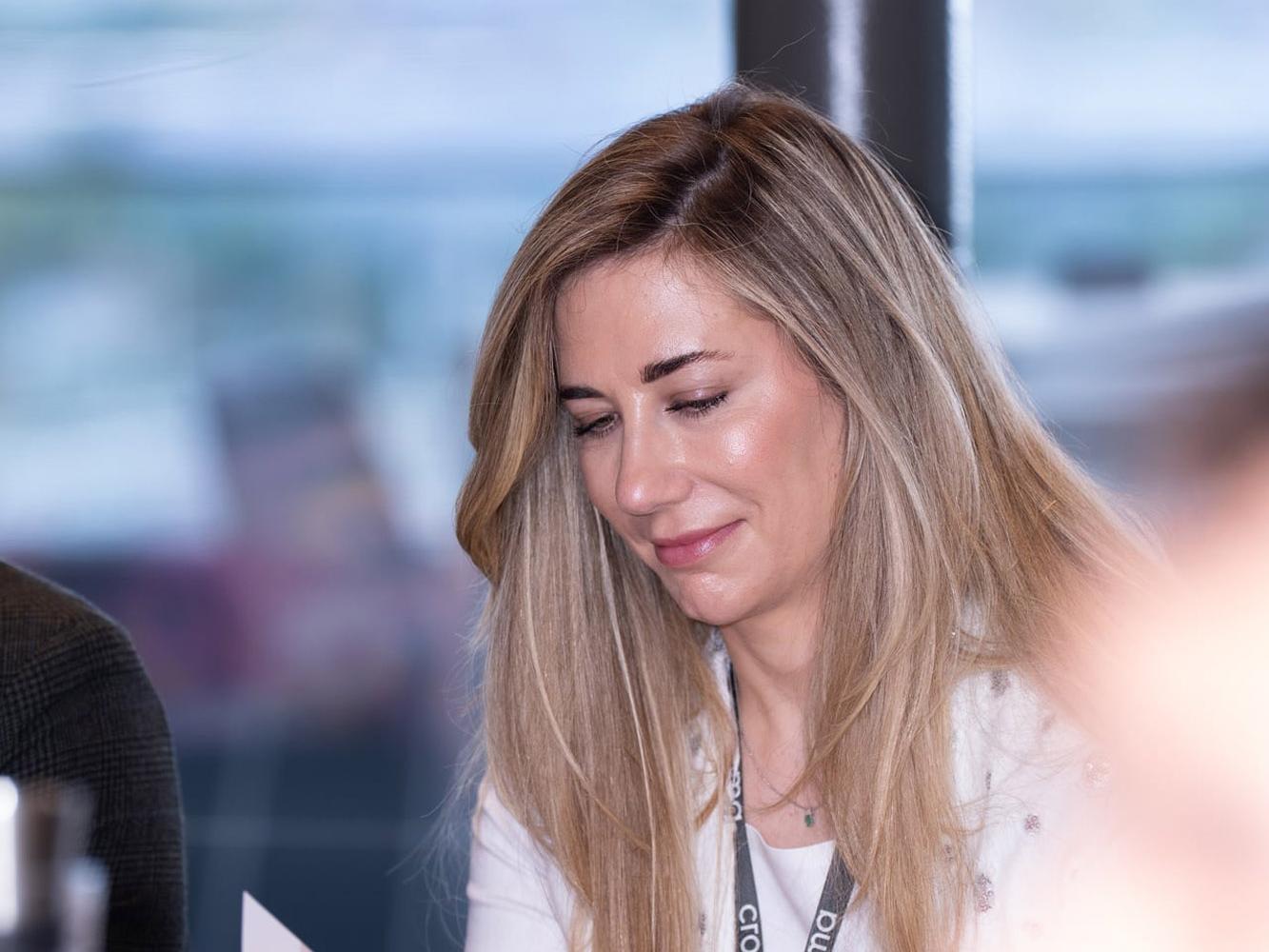 Frau mit Croma-Umhängeband liest eine Broschüre an einem Konferenztisch