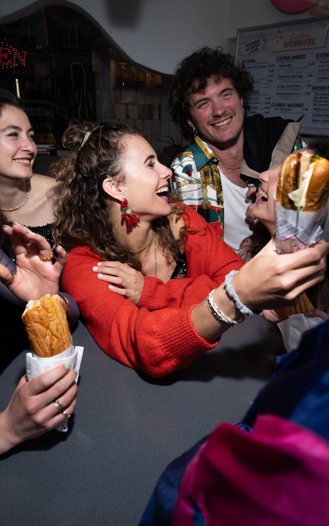 Gruppe junger Leute lacht und teilt Baguettes auf einer Feier