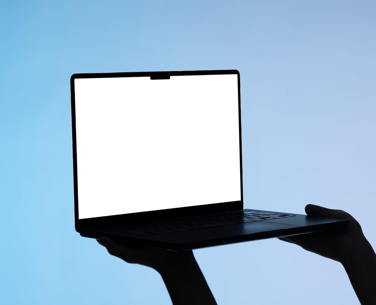Laptop-Mockup mit leerem Bildschirm vor blauem Hintergrund, von zwei Händen gehalten
