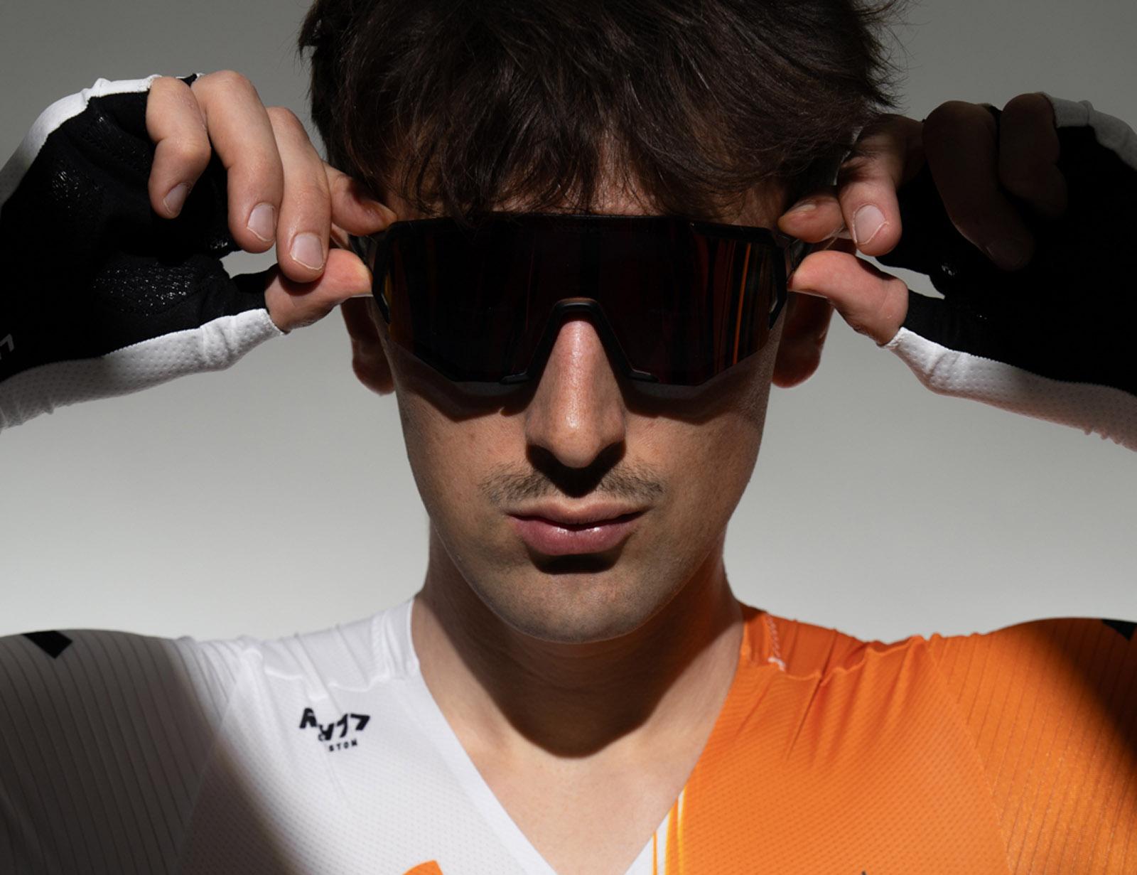 Radsportler im orange-weißen Trikot mit Sonnenbrille, Nahaufnahme