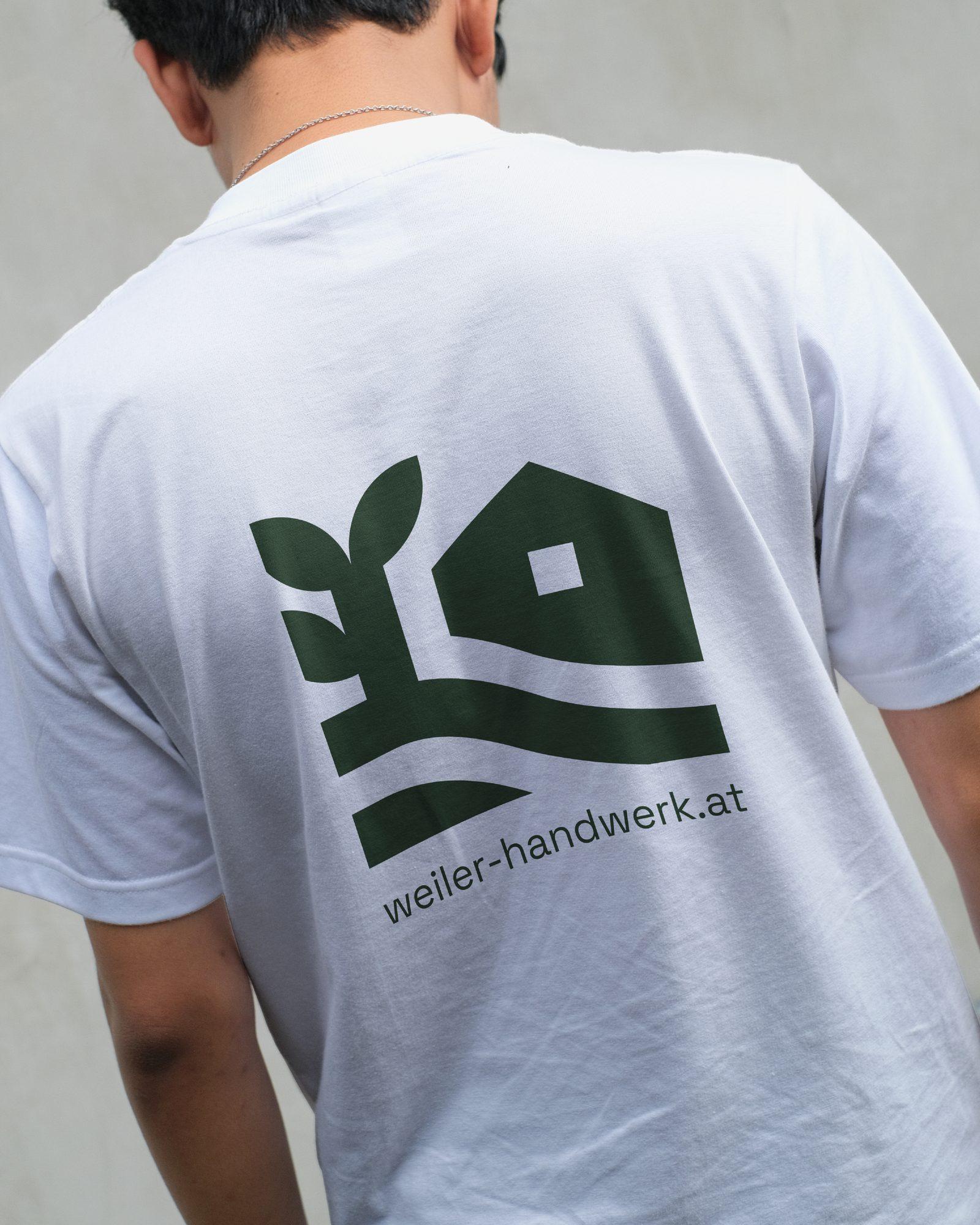 Weißes Weiler Shirt mit grünem Logo und weiler-handwerk.at auf dem Rücken