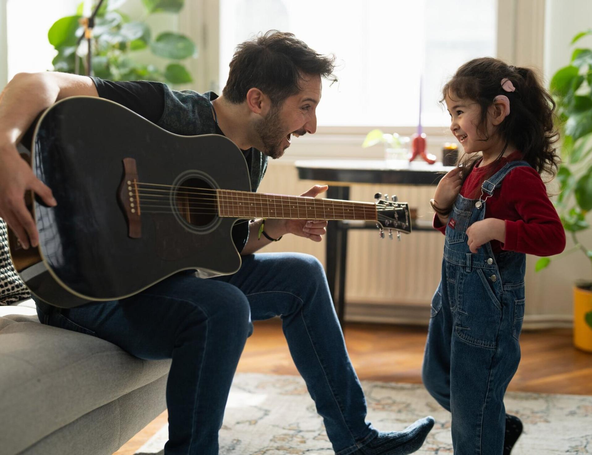 Vater spielt Gitarre, die kleine Ayla tanzt im Wohnzimmer