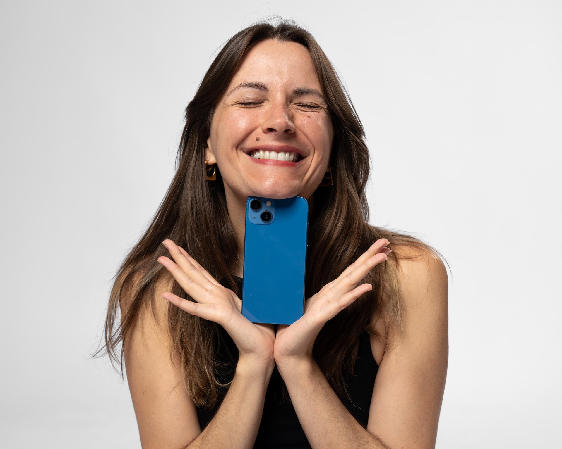 Mia Kordesch hält lachend ein blaues Smartphone vors Gesicht
