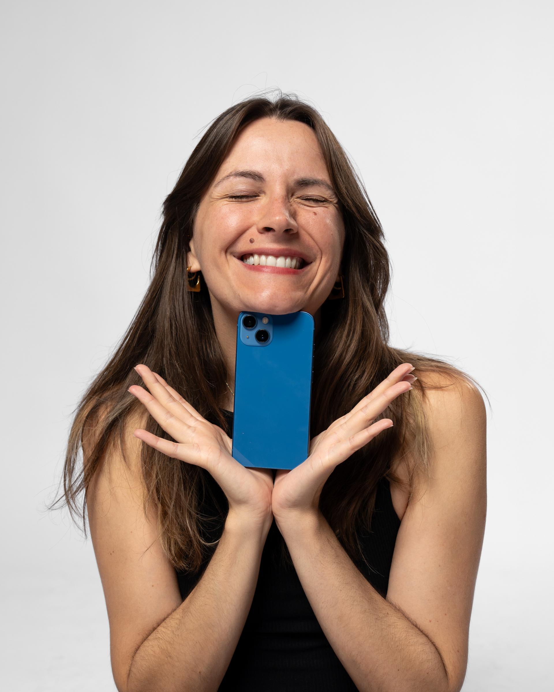 Mia Kordesch hält lachend ein blaues Smartphone vors Gesicht