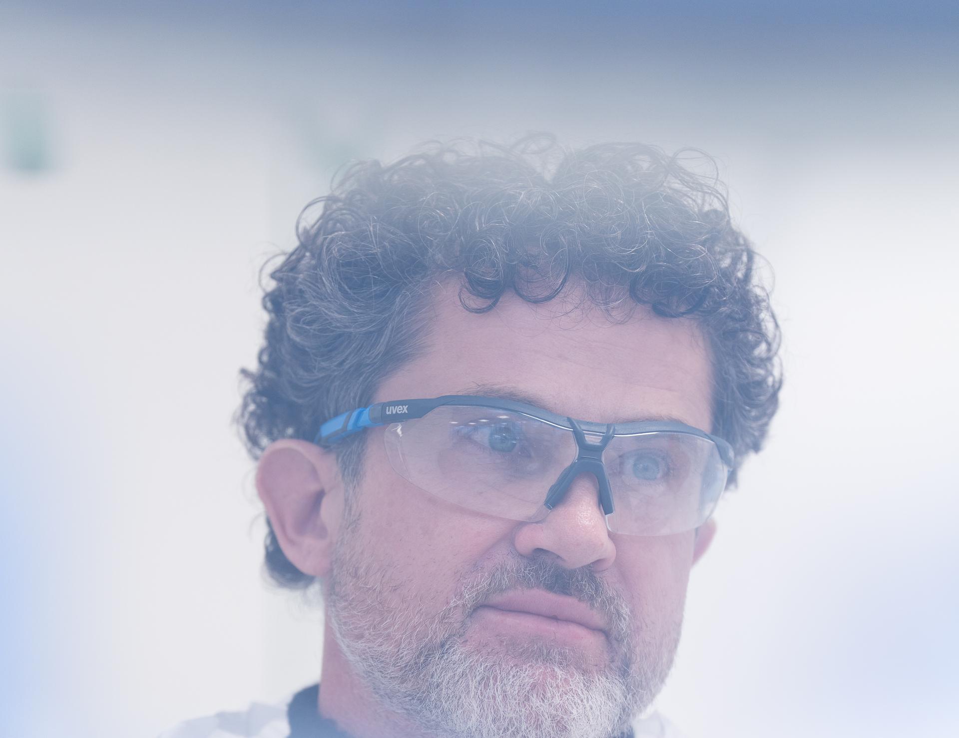 Mann mit Brille und Bart hinter einer milchigen Glasfläche