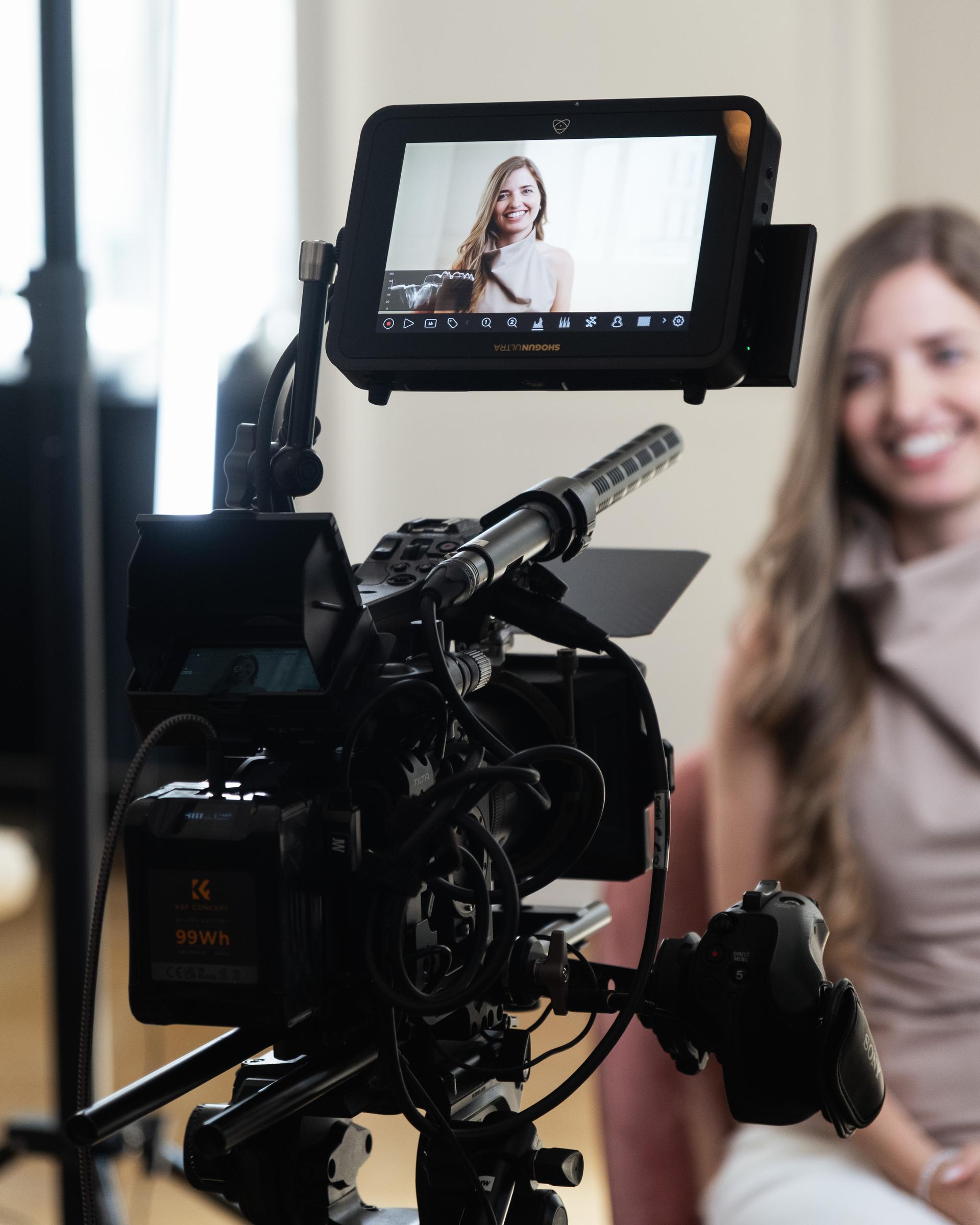 Videokamera mit Monitor filmt eine lächelnde Frau bei einem Interview