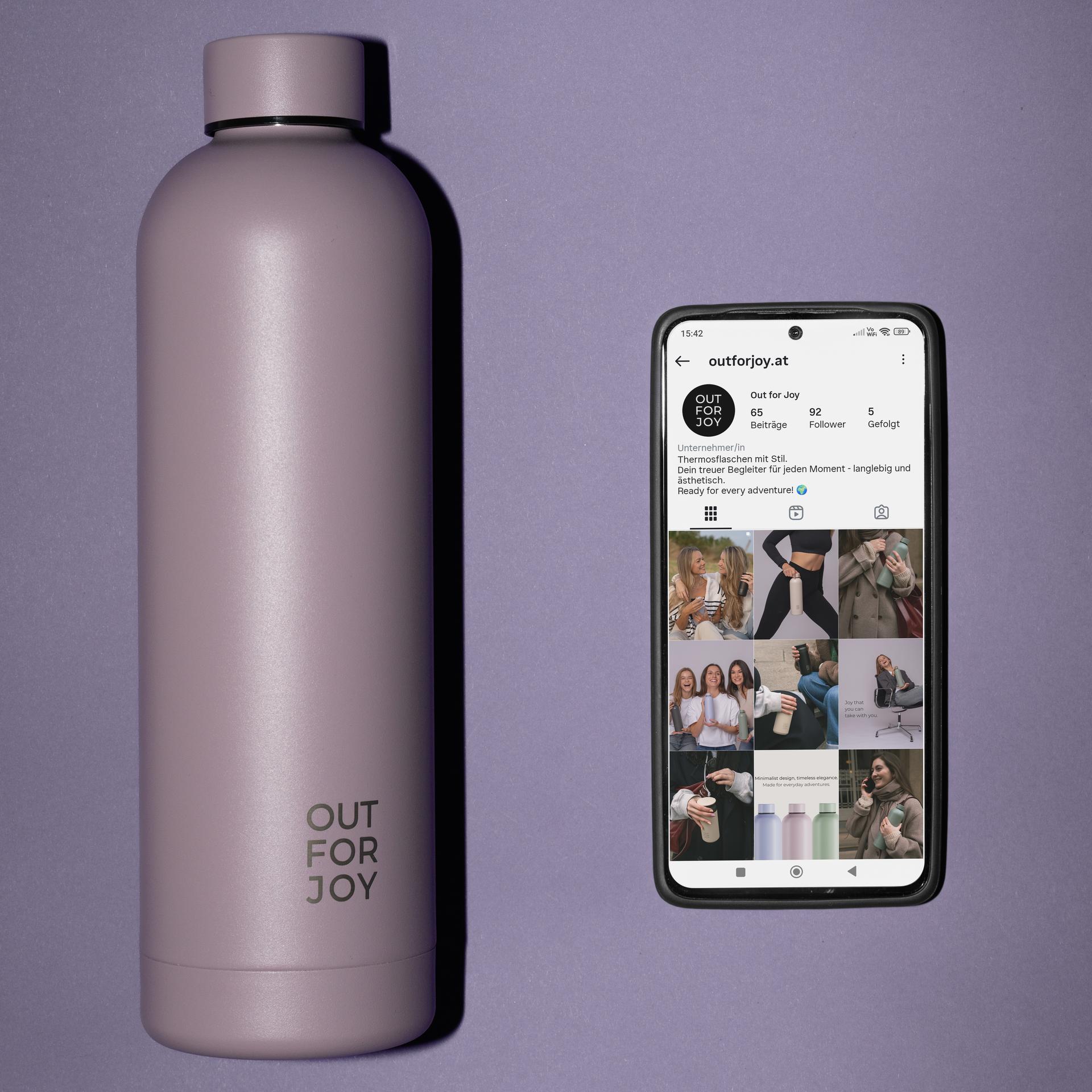 Violette Trinkflasche neben einem Smartphone mit Instagram-Profil