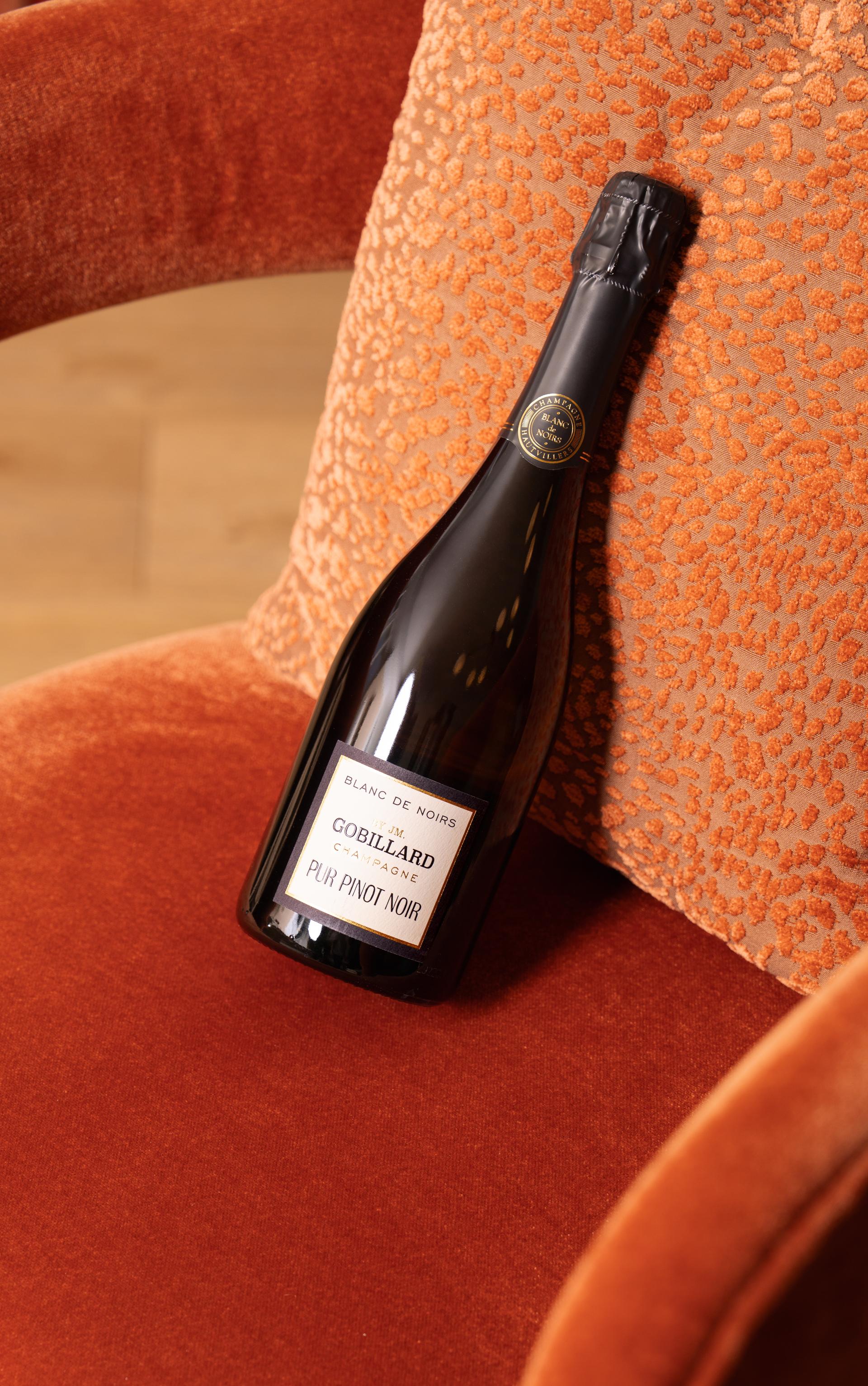 Flasche Gobillard Blanc de Noirs auf einem orangen Sessel
