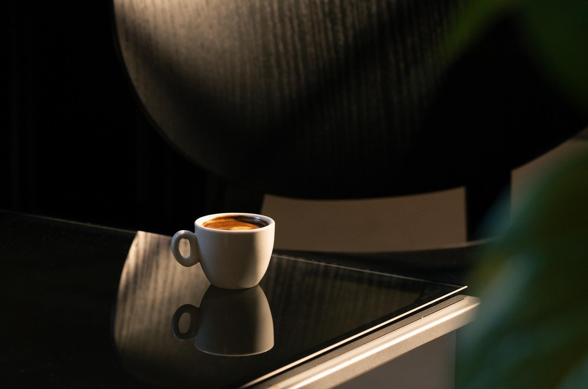Espressotasse auf dunkler Fläche im Gegenlicht