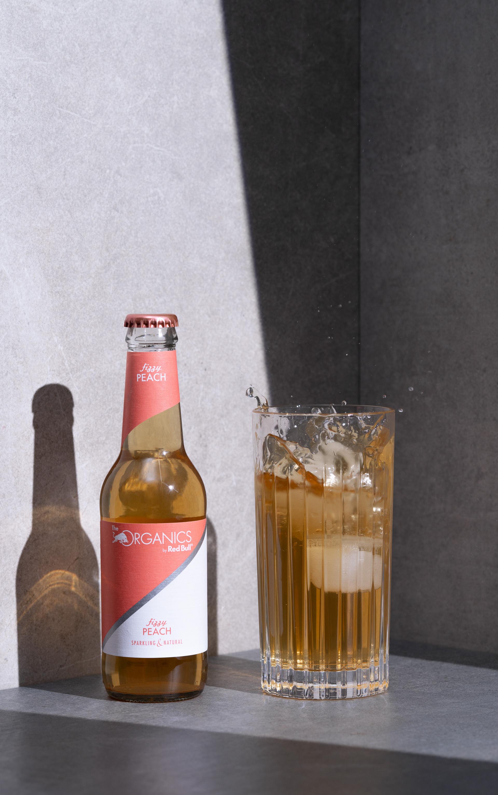 Bierflasche und Glas mit Spritzern vor heller Wand