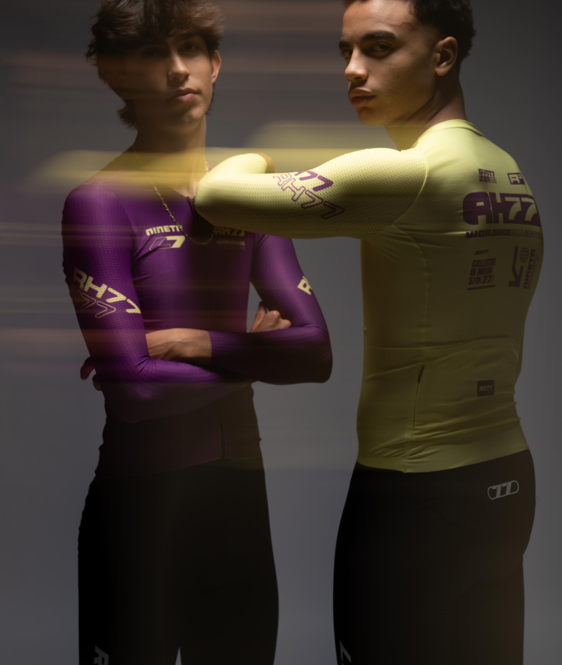 Zwei Sportler in RH77-Trikots, violett und gelb, vor dunklem Hintergrund mit Lichtschlieren
