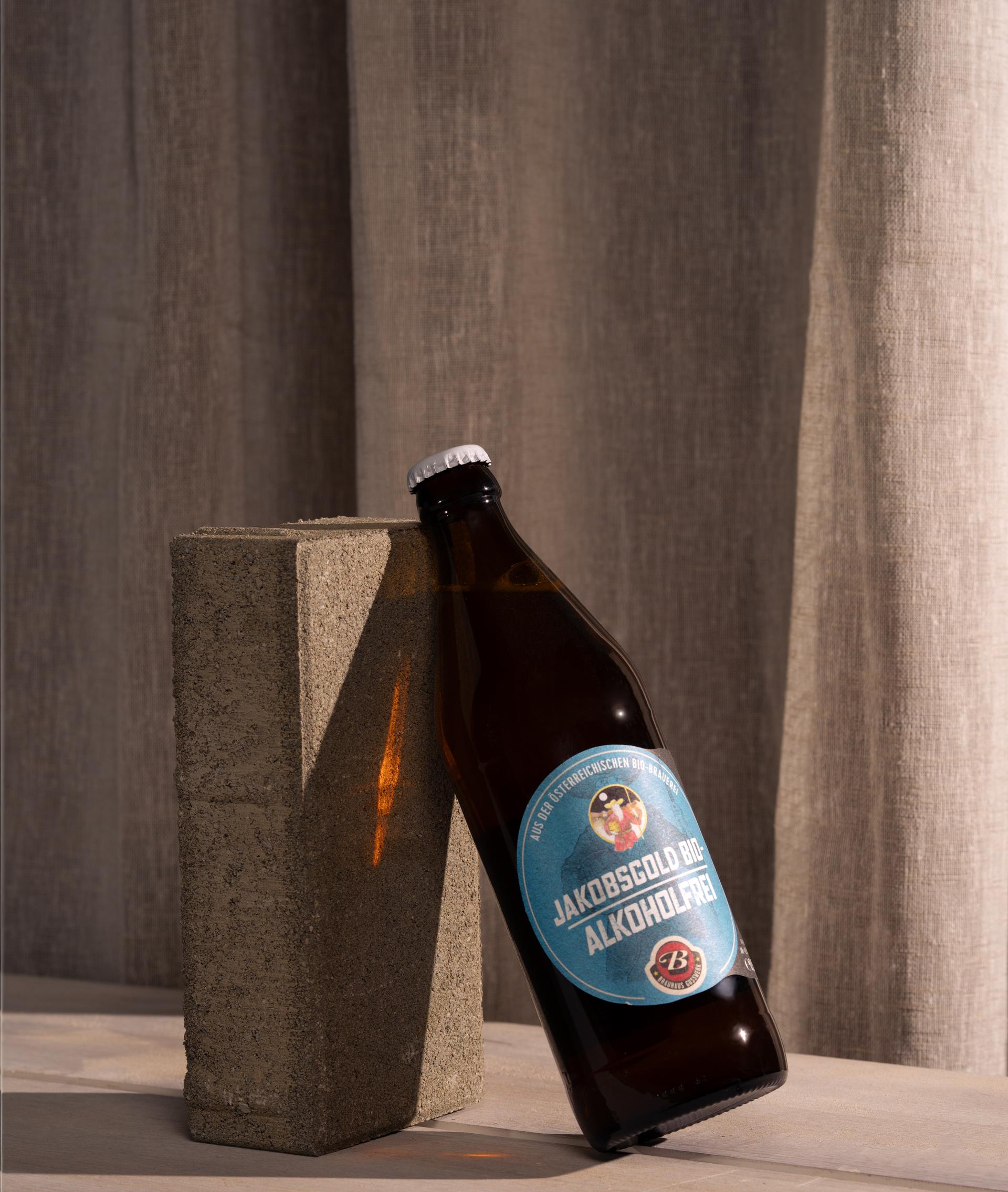 Bierflasche lehnt an einem Betonstein vor Vorhang