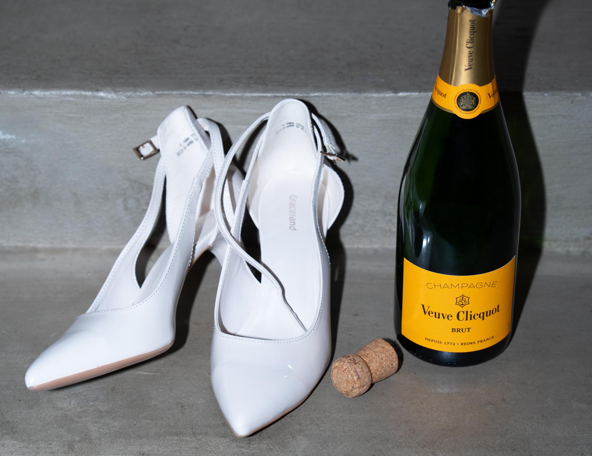 Weiße Pumps neben einer Flasche Veuve Clicquot