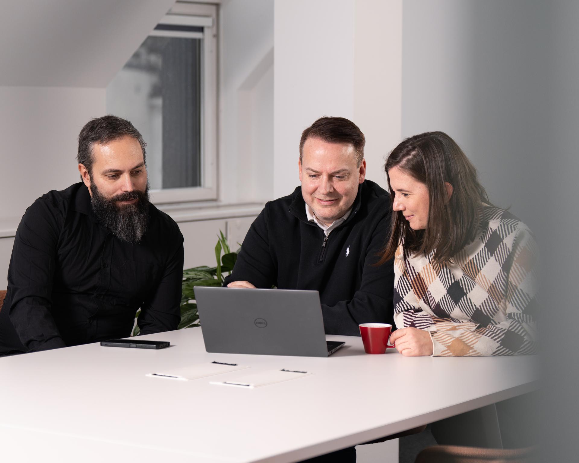 Drei Personen arbeiten gemeinsam an einem Laptop