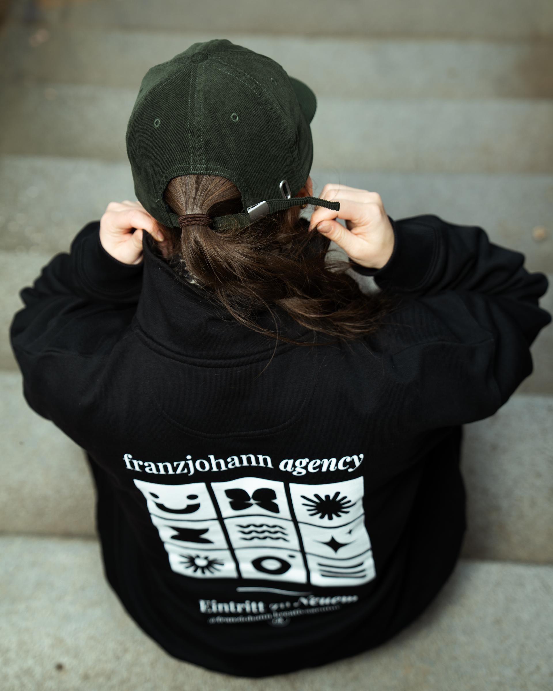 Rückansicht einer Person im schwarzen Hoodie mit franzjohann-agency-Print