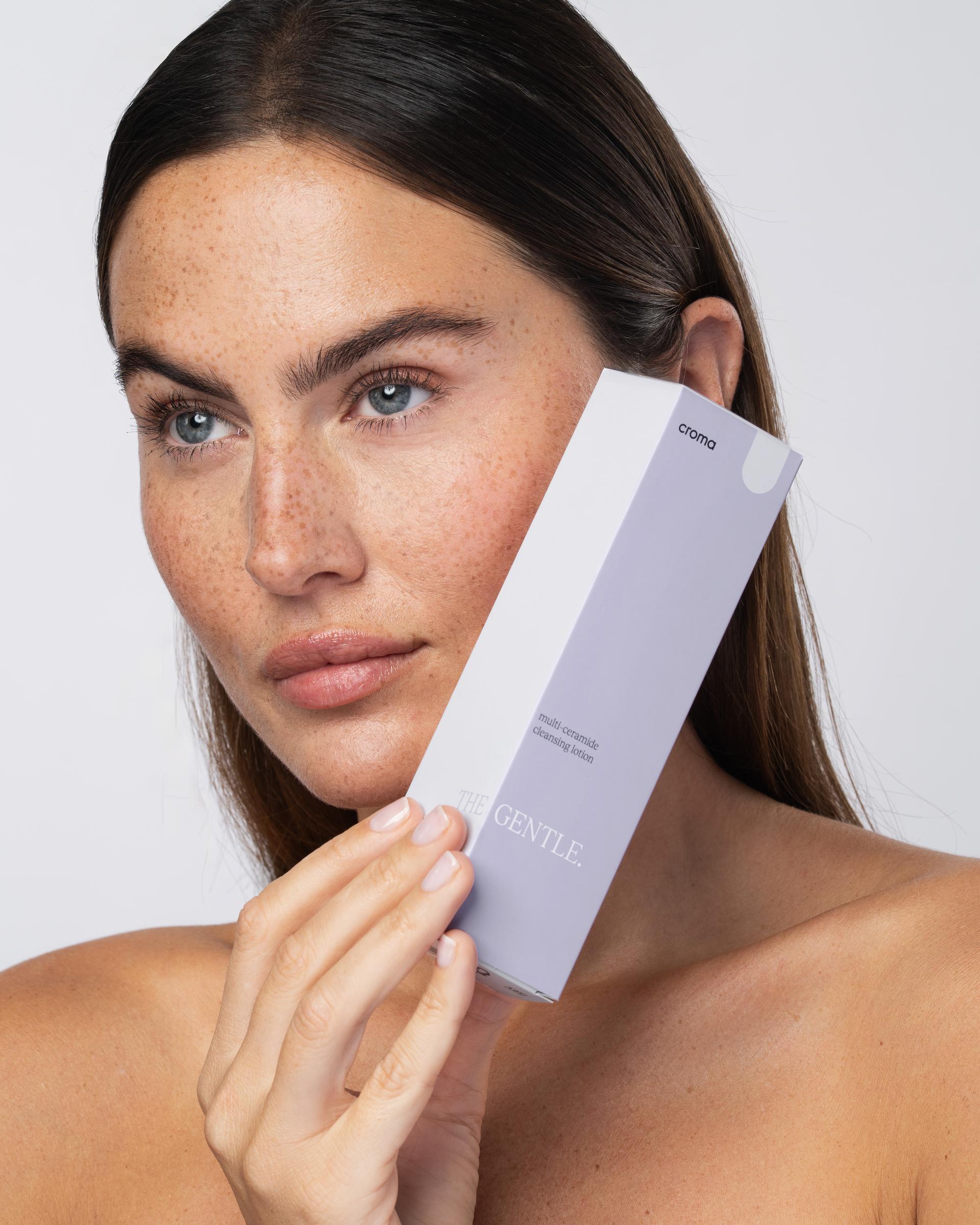 Frau mit Sommersprossen hält eine Croma-Gentle-Verpackung ans Gesicht