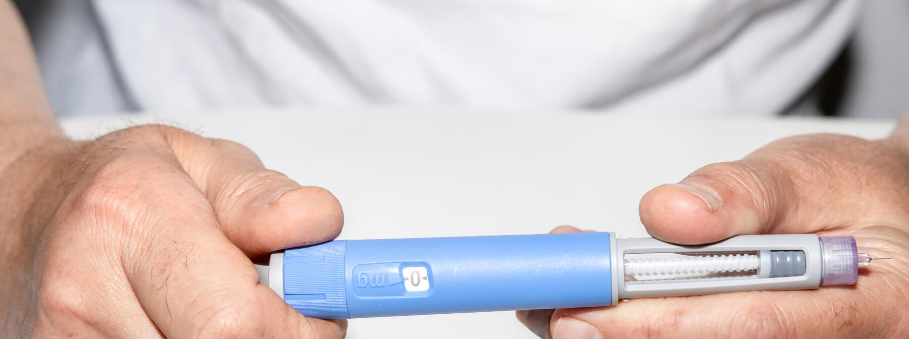 A person holding a blue GLP-1 injector pen