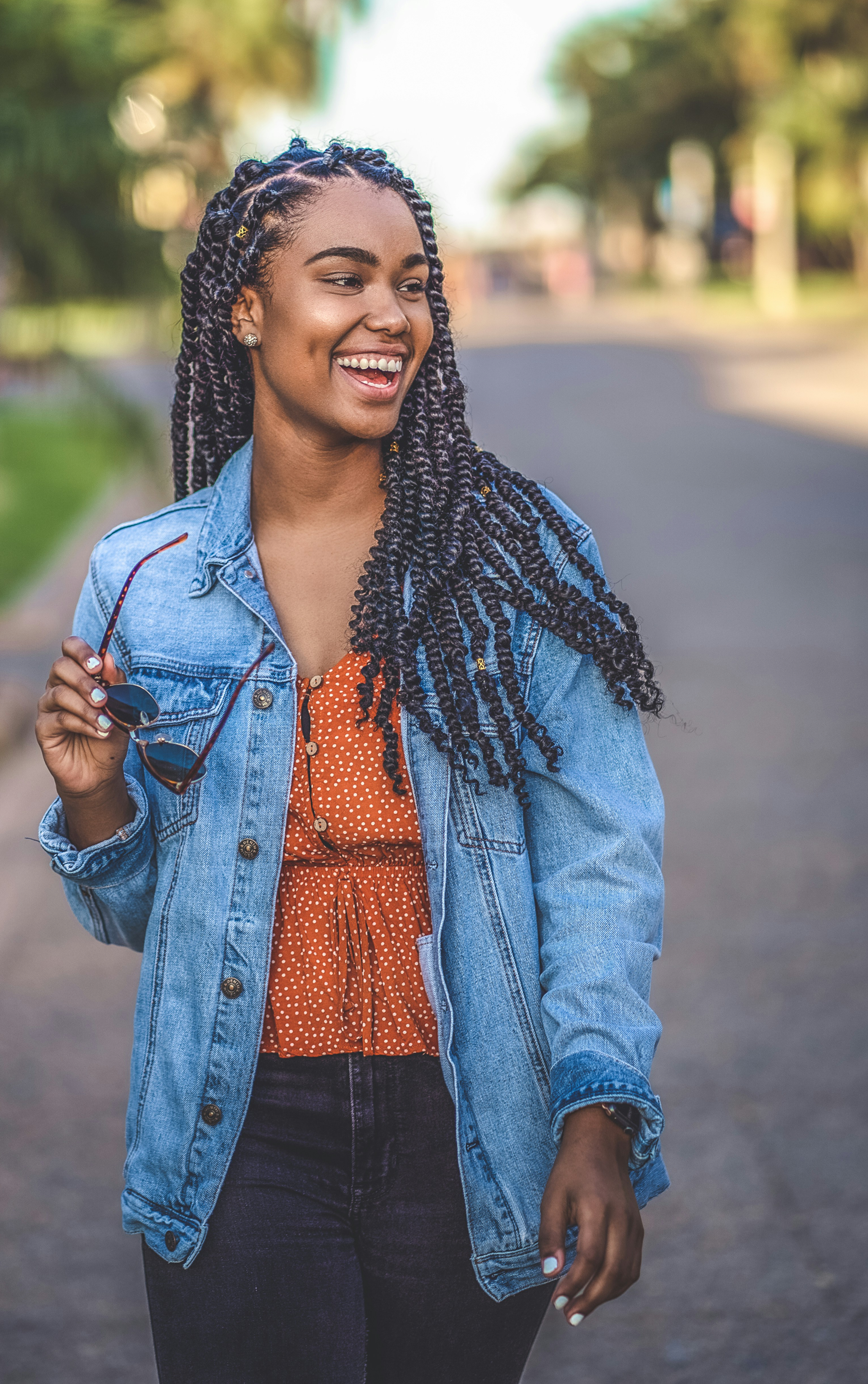 Woman walking on street while smiling with sunglasses