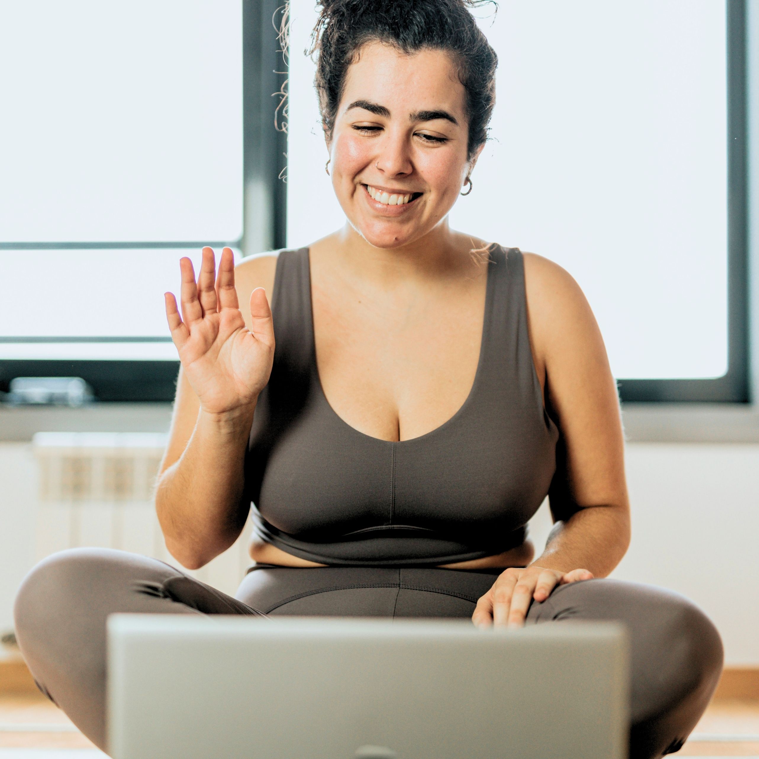 A woman saying hi to a computer screen smiling