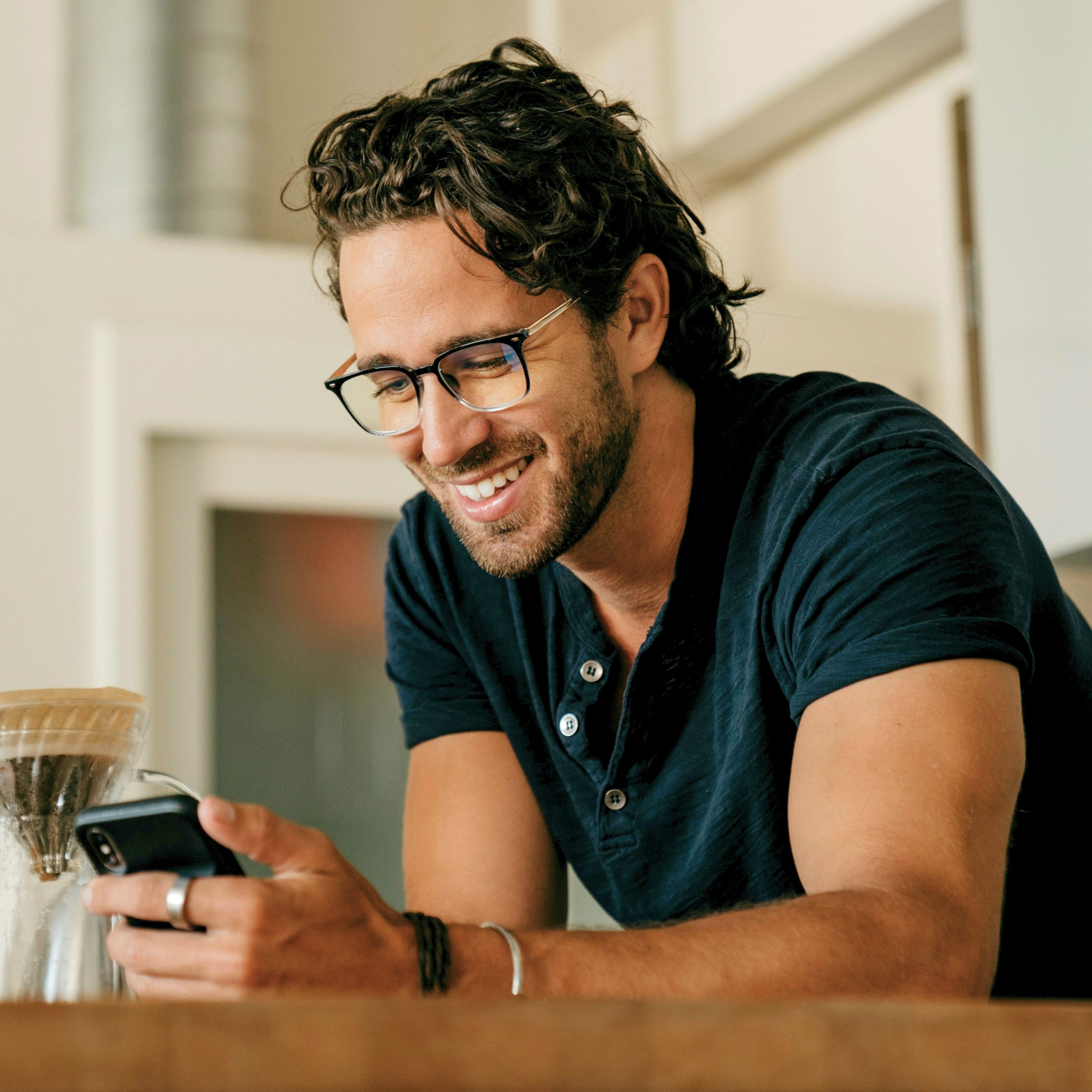 A man smiling while looking into a phone