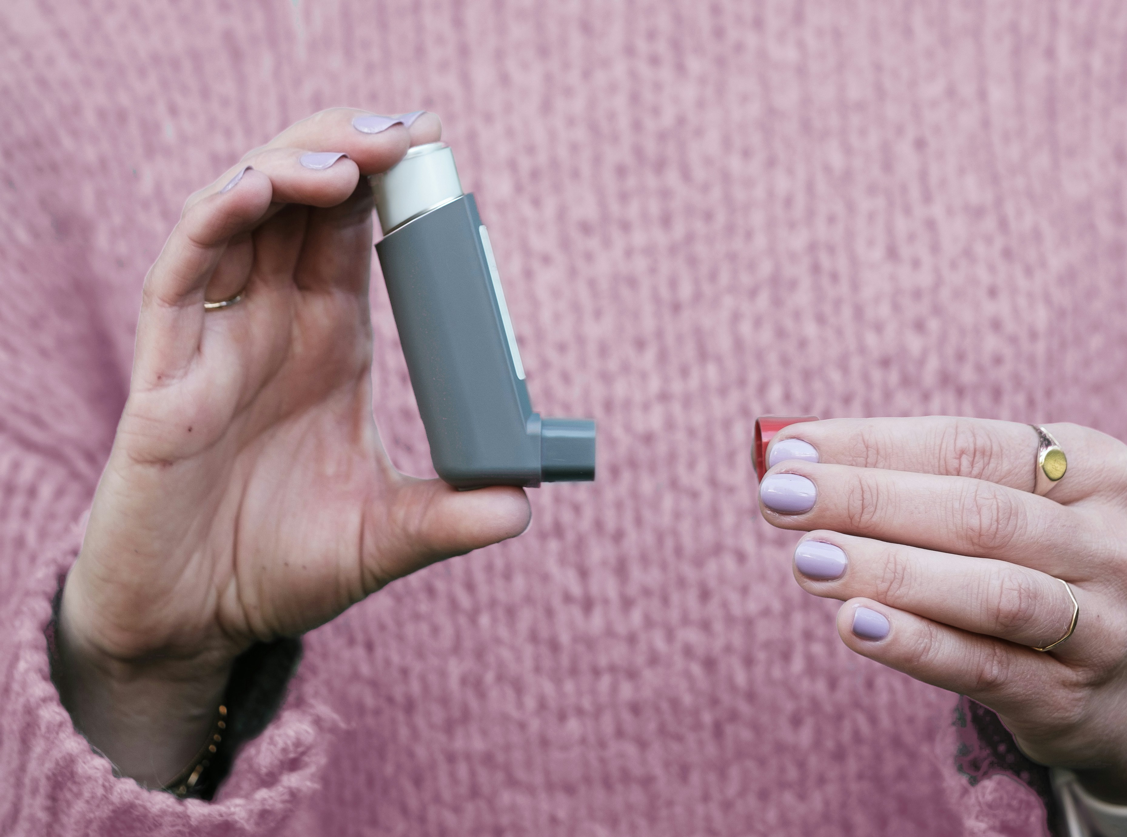 Man at home breathing in from a metered-dose asthma inhaler